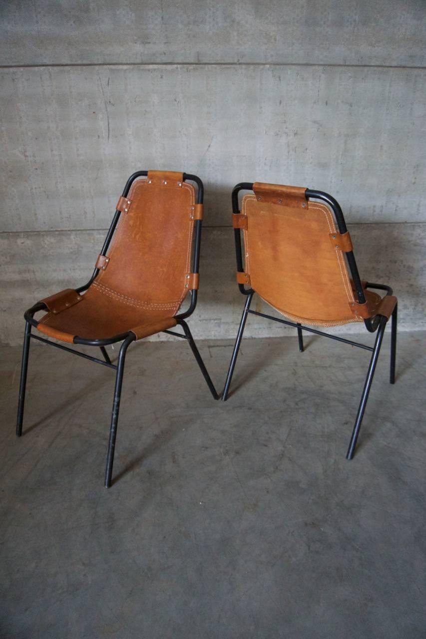 This chair was designed by Charlotte Perriand for Les Arcs during the 1960s. It features a black tubular frame with thick cognac leather seats. The leather seat is missing some stitches and the stitching in the middle is redone.