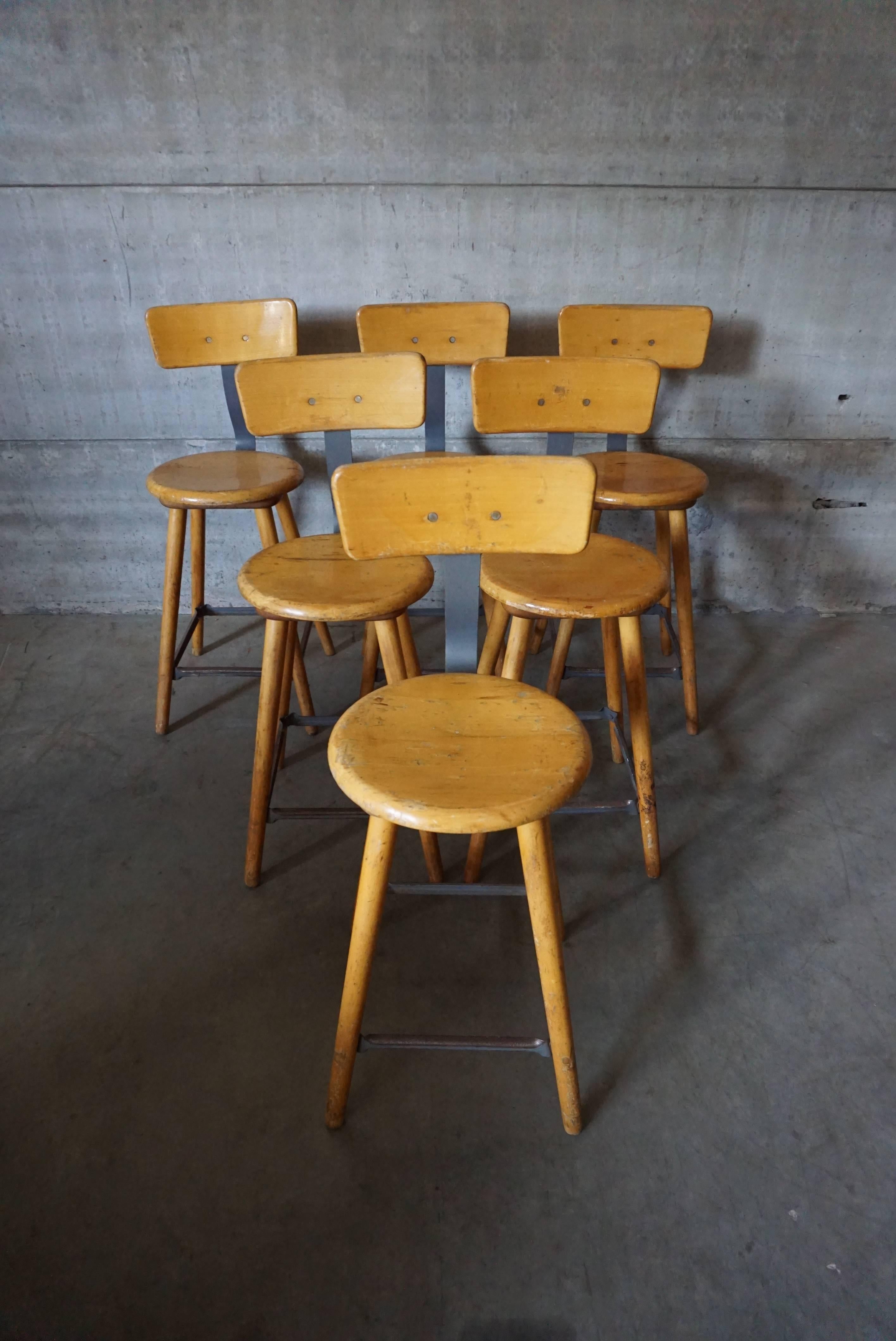 This workshop stool was made in Germany in the 1950s. It features a wooden frame, seat and backrest. It can be used as a bar stool.