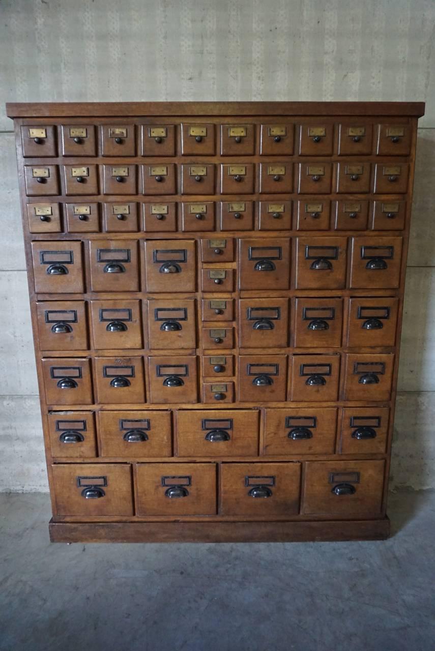 This apothecary bank of drawers was designed and made circa 1920-1930. It is made from oak with cup handles and brass hardware.