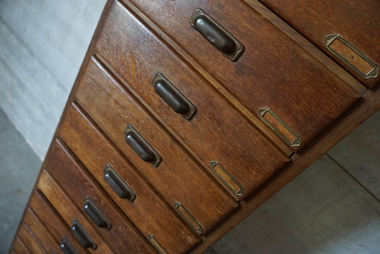 This apothecary cabinet was designed and made, circa 1920-1930. It is made from oak with cup handles and brass hardware.