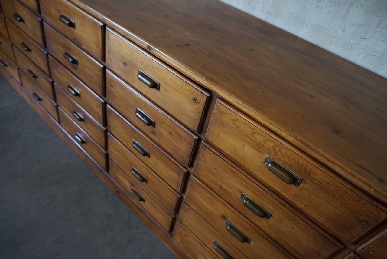 This apothecary bank of drawers was designed and made, circa 1930 in Germany. The piece is made from pine with brass hardware.