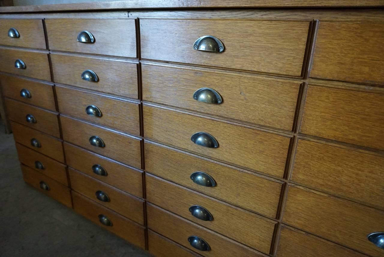 This apothecary bank of drawers was designed and made around the 1950s. The piece is made from oak with cup handles.