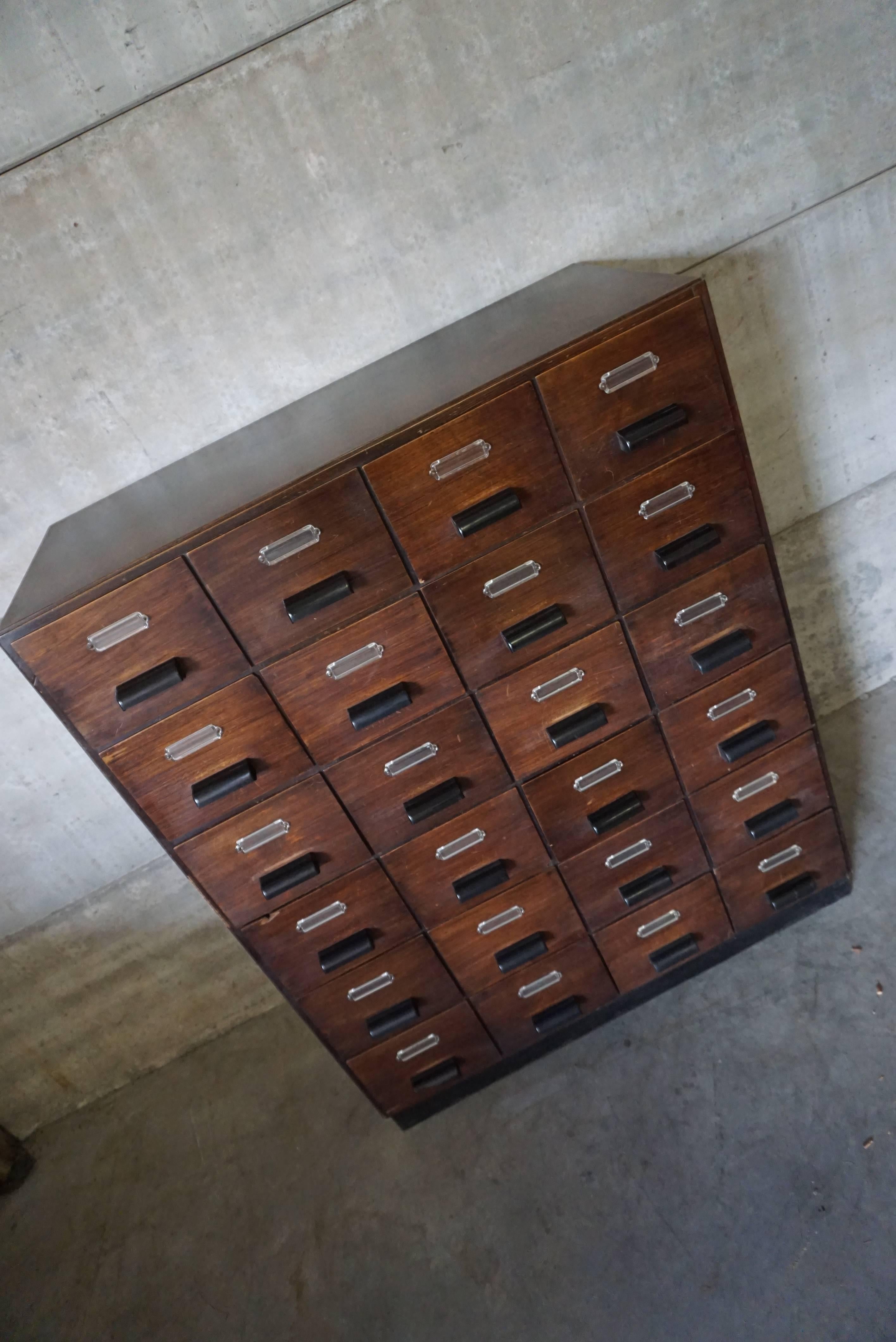 This Industrial wooden filing cabinet is made from oak veneer with bakelite handles and was designed and made in the 1950s. It is in a good vintage condition with signs of use consistent with age.