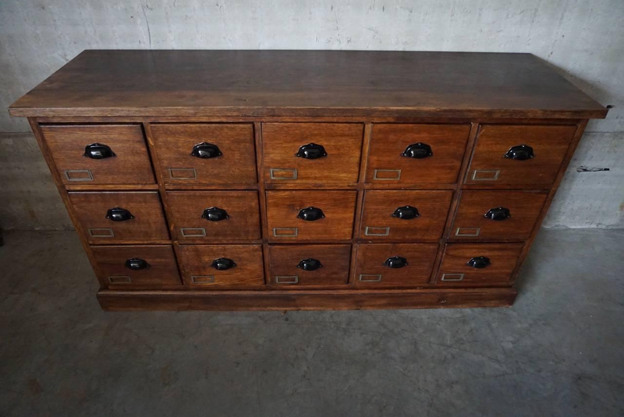 This apothecary bank of drawers was designed and made, circa 1920-1930. The piece is made from oak with cup handles and brass hardware.