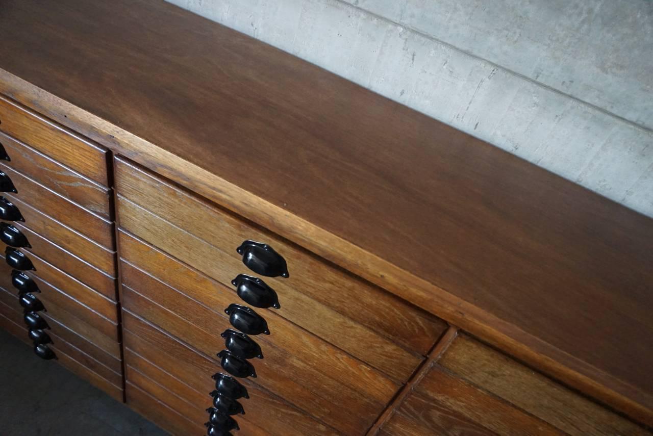 This apothecary bank of drawers was designed and made circa 1950s. The piece is made from oak fronts with cup handles. Some drawers have a divider which can be removed.