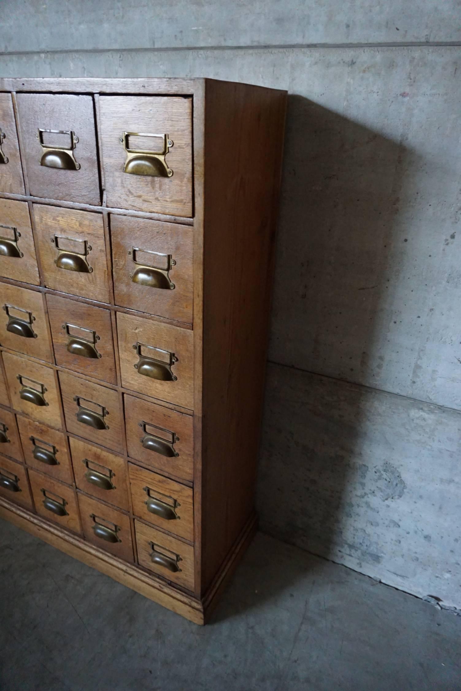 This apothecary bank of drawers was designed and made around the 1930s. The drawer fronts are made from oak with brass hardware.
