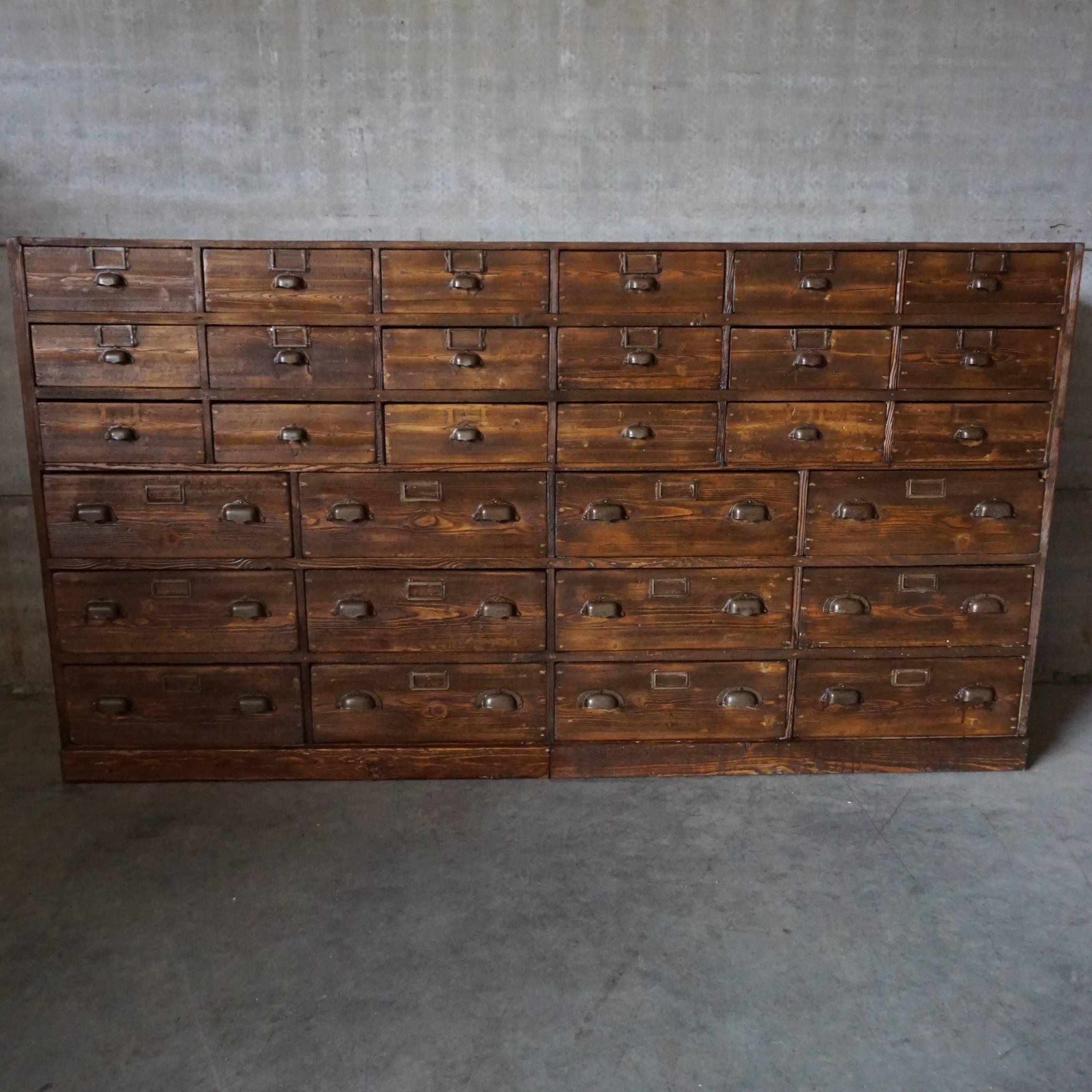 This apothecary bank of drawers was designed and made around 1920-1930. The piece is made from pine with cup handles. Some drawers have a divider which can be removed as a tray.