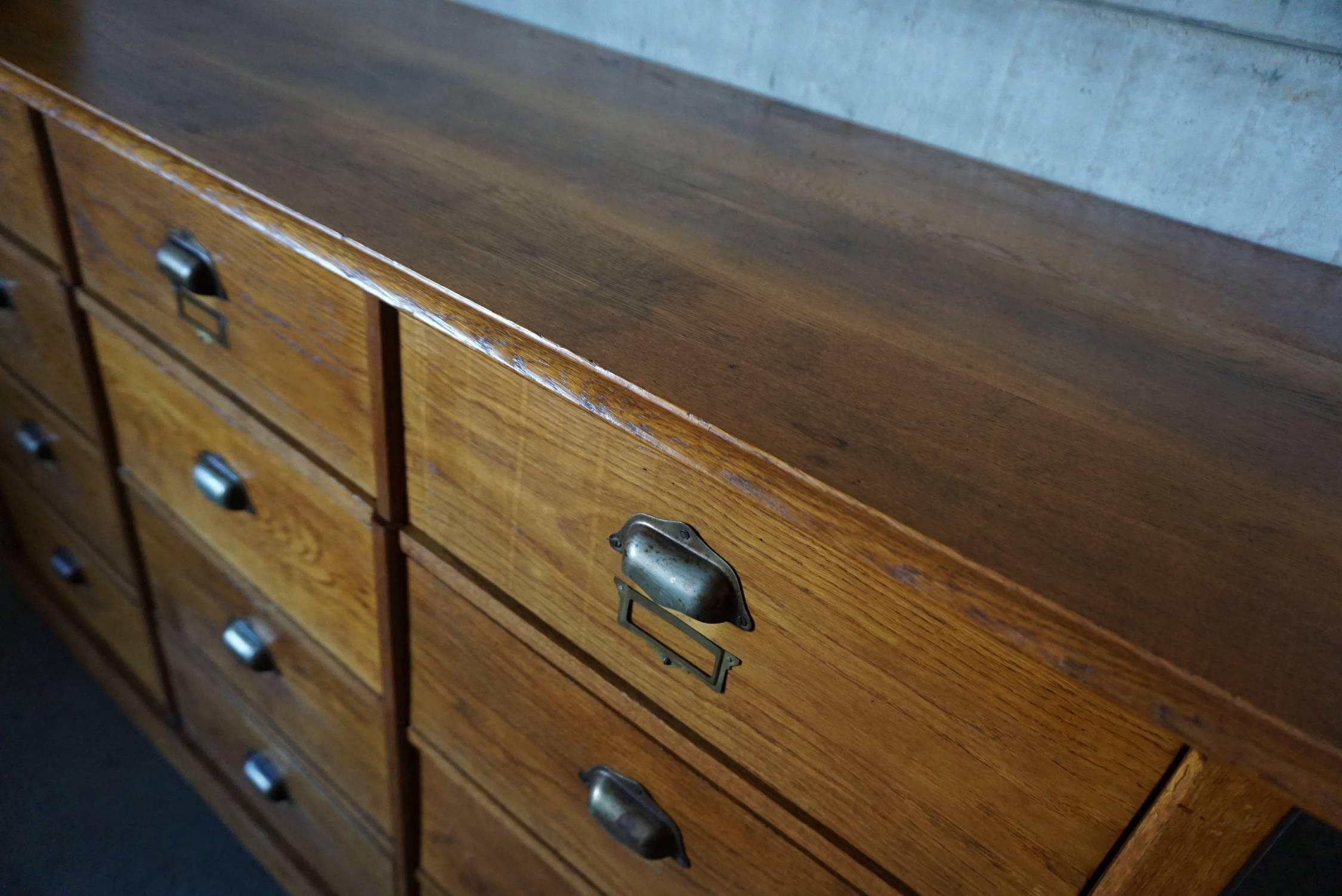 This apothecary bank of drawers was designed and made around the 1930s in France. The piece is made from oak with cup handles and brass hardware.