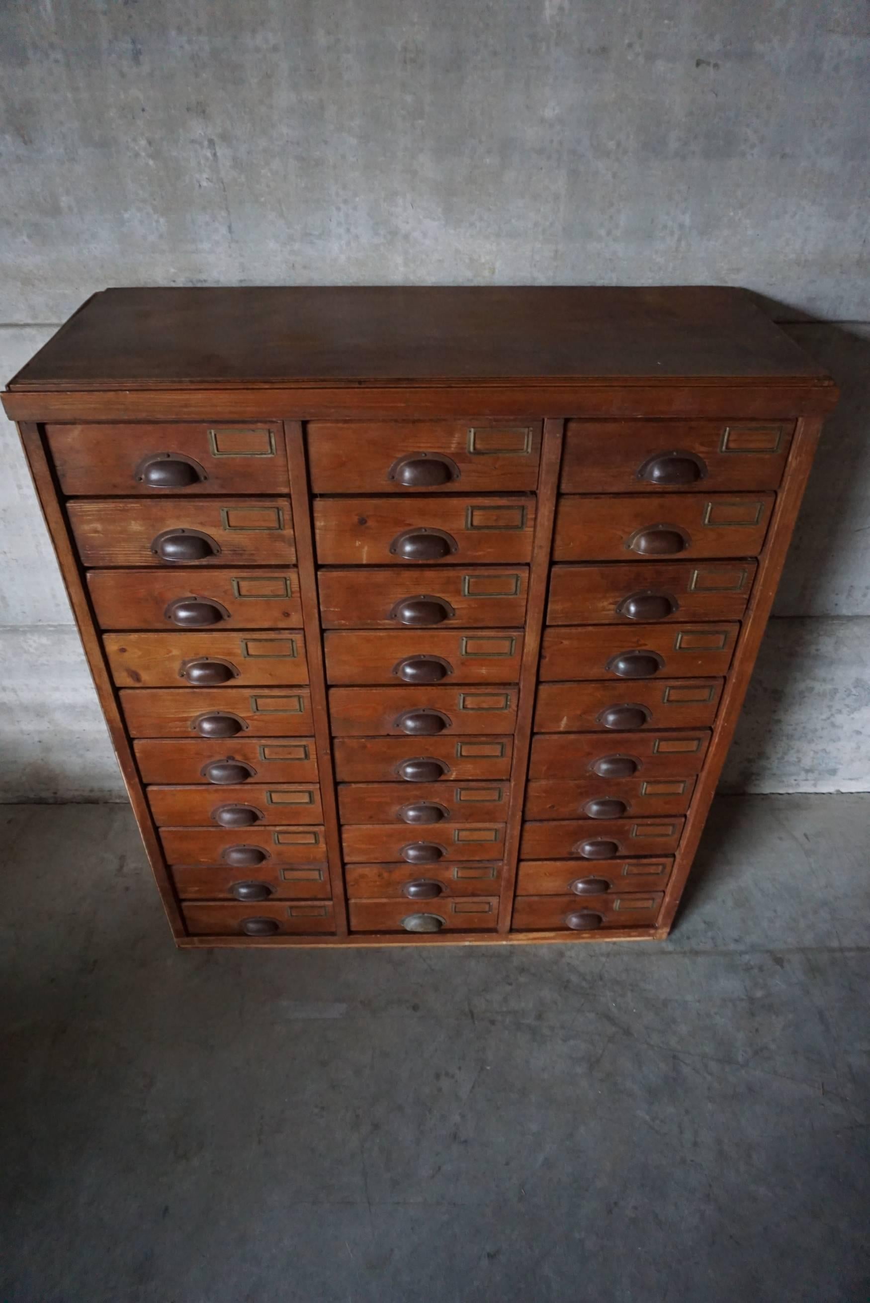 This apothecary bank of drawers was designed and made around the 1930s. The piece is made from pine with cup handles.