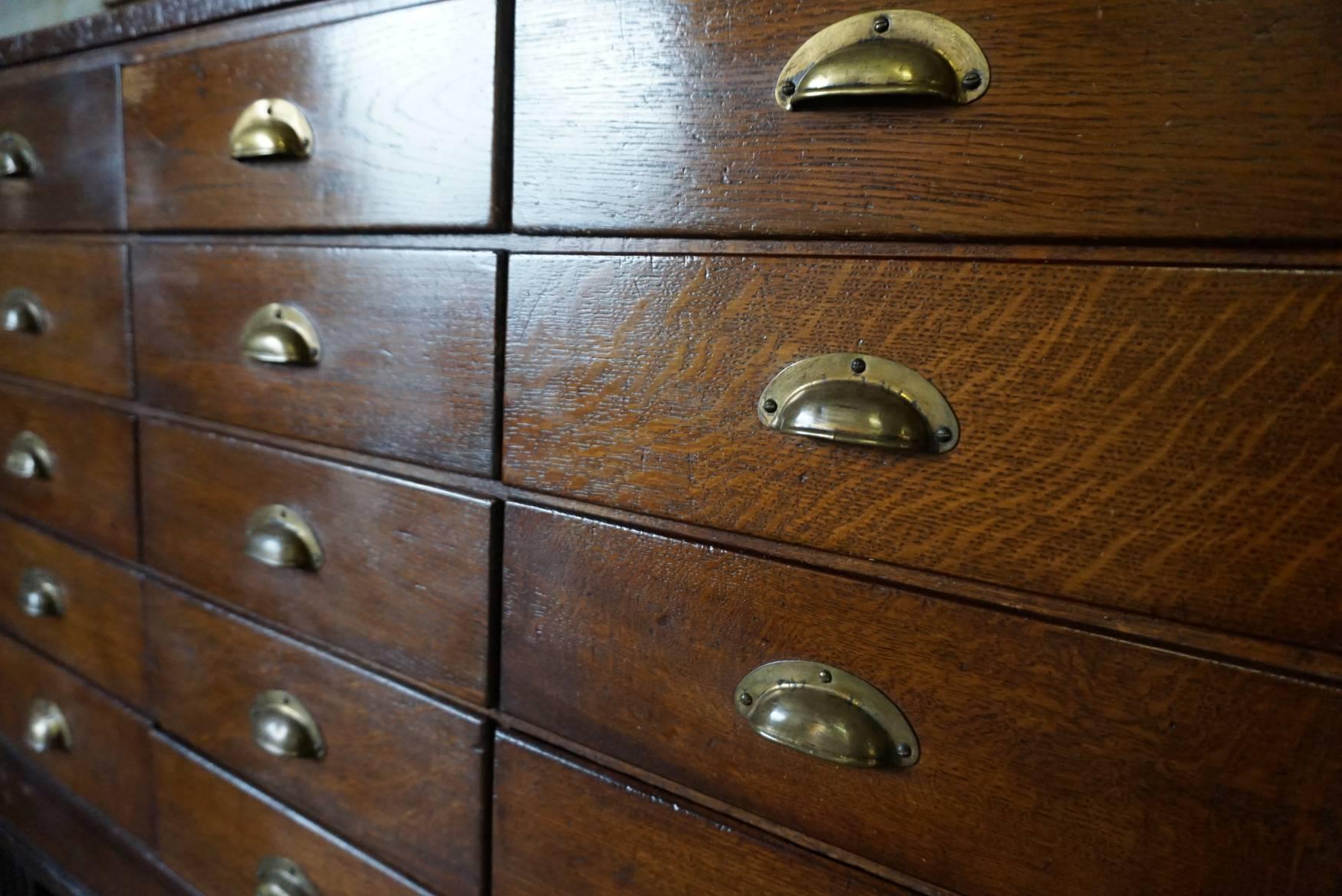 Vintage oak haberdashery shop counter dating from the 1930s. It features a solid wooden frame and oak drawer fronts with metal cup handles. The glass is in good condition and the drawers run smoothly.