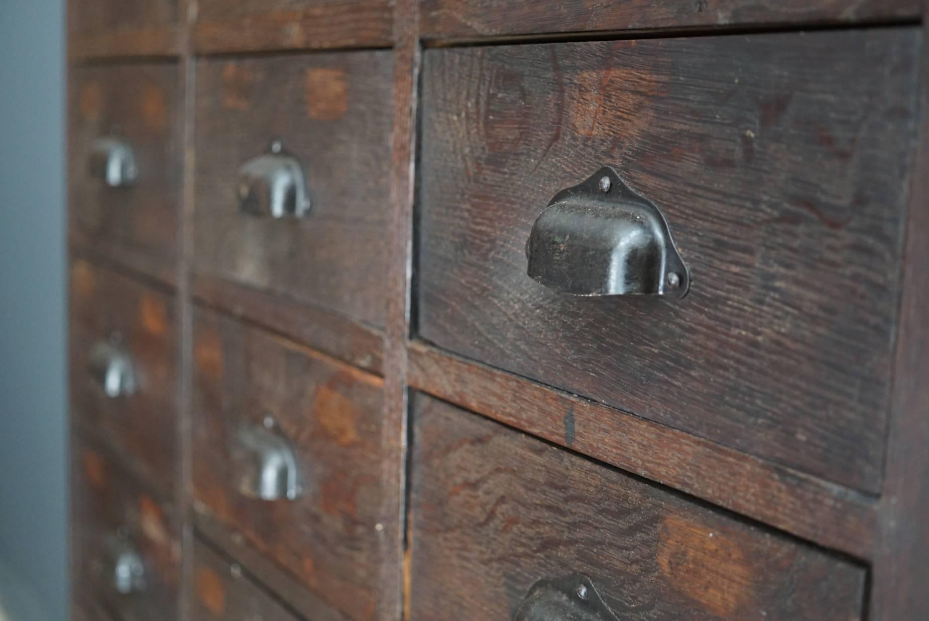 This apothecary bank of drawers was designed and made, circa 1930. The piece is made from oak with cup handles.