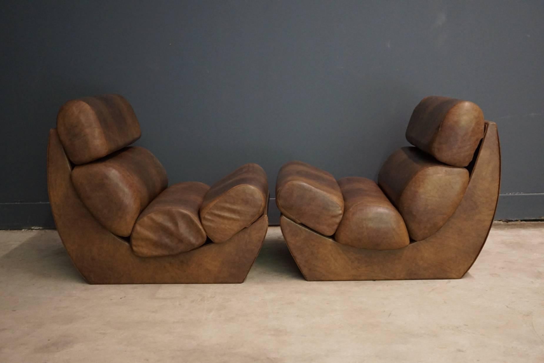 This pair of faux leather club chairs were designed and made around the 1970s in Italy. They feature a wooden box upholstered with faux leather and four cushions.