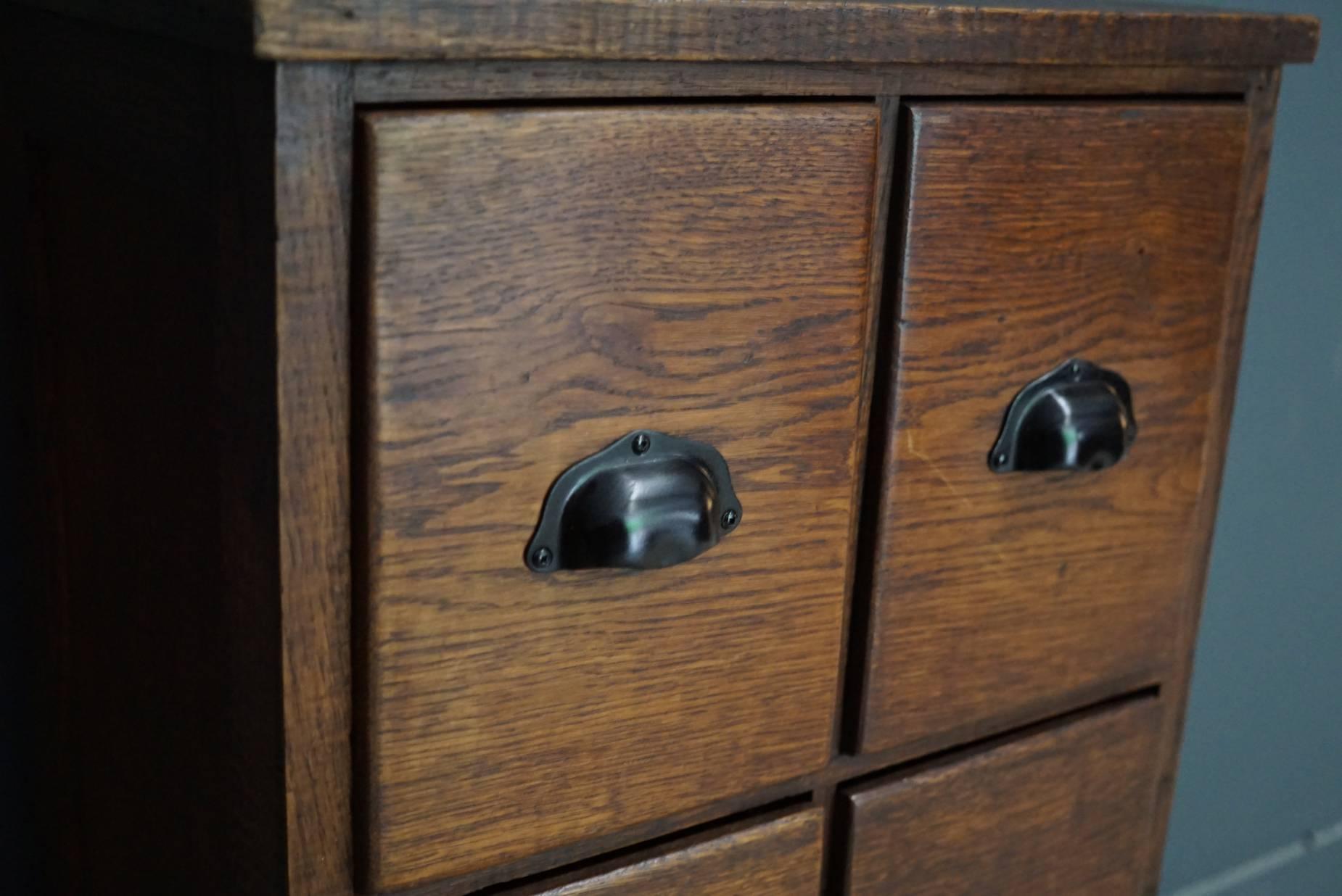 This apothecary cabinet of drawers was designed circa during the 1930s in France. The piece is made from oak and features drawers with metal handles and panelled sides.