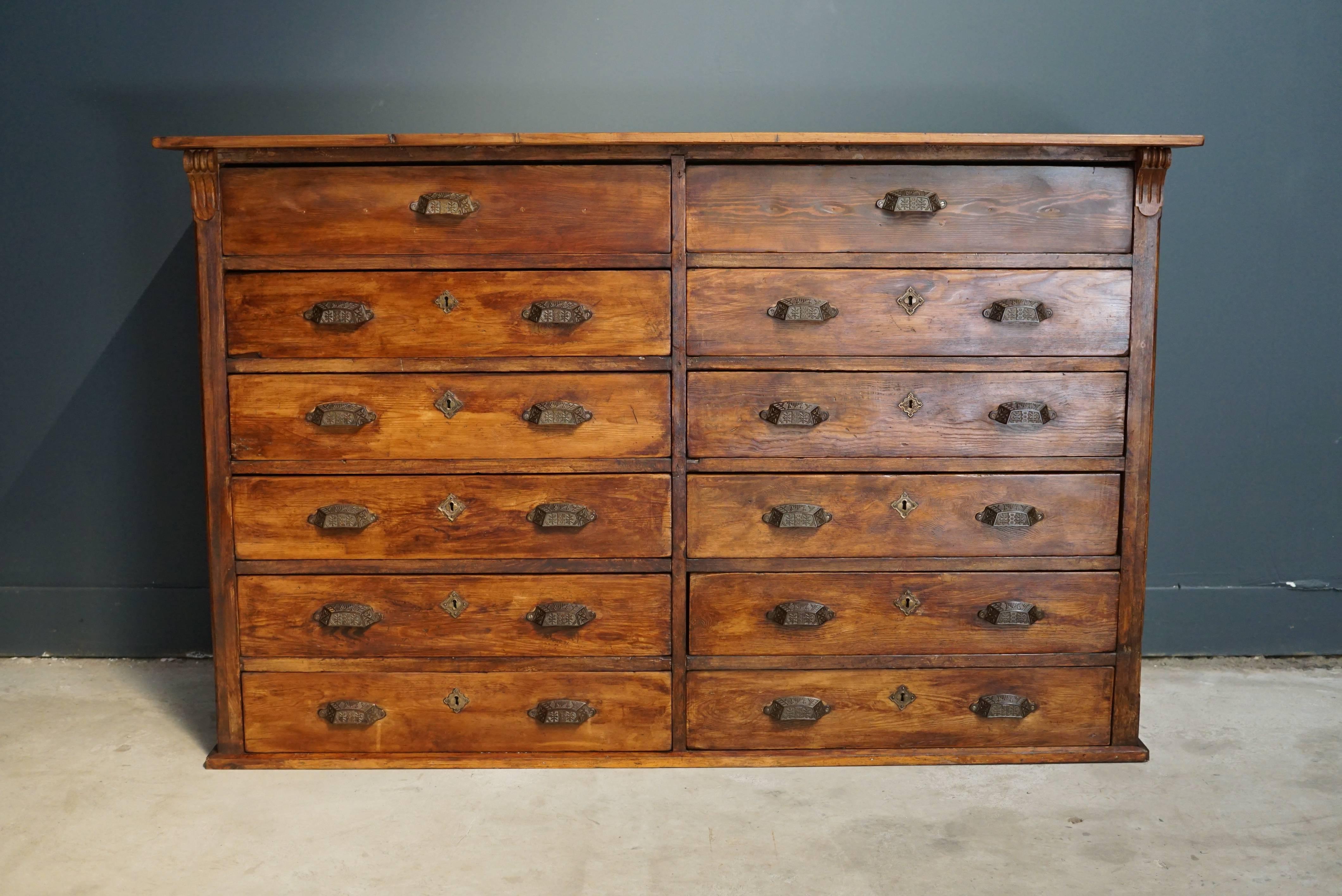 This apothecary cabinet of drawers was designed, circa 1920s in France. The piece is made from pine and features eight large drawers with cast iron handles.