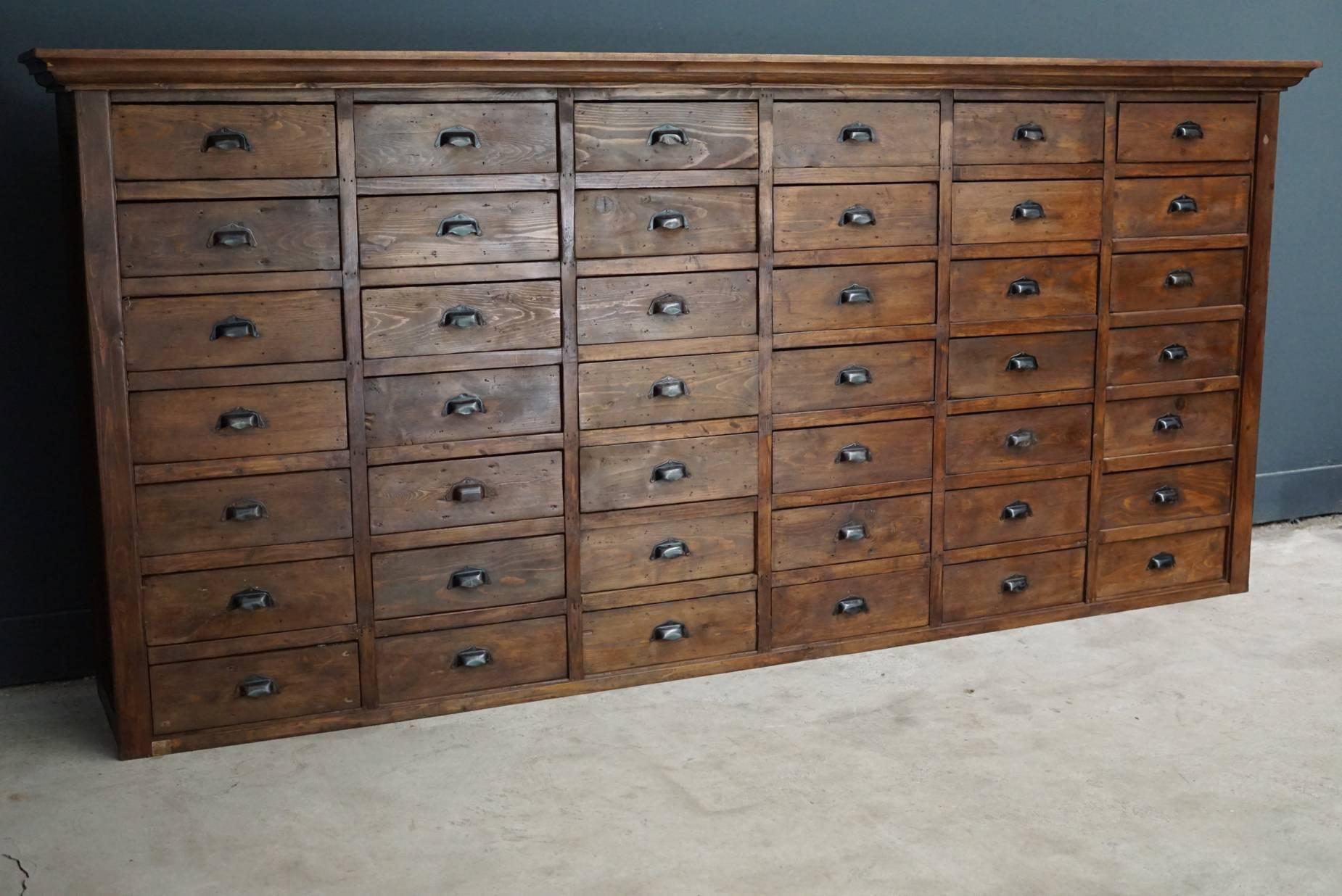 This apothecary cabinet of drawers was designed and made circa 1950s in France. The piece is made from pine and features 42 drawers with metal cup handles.
