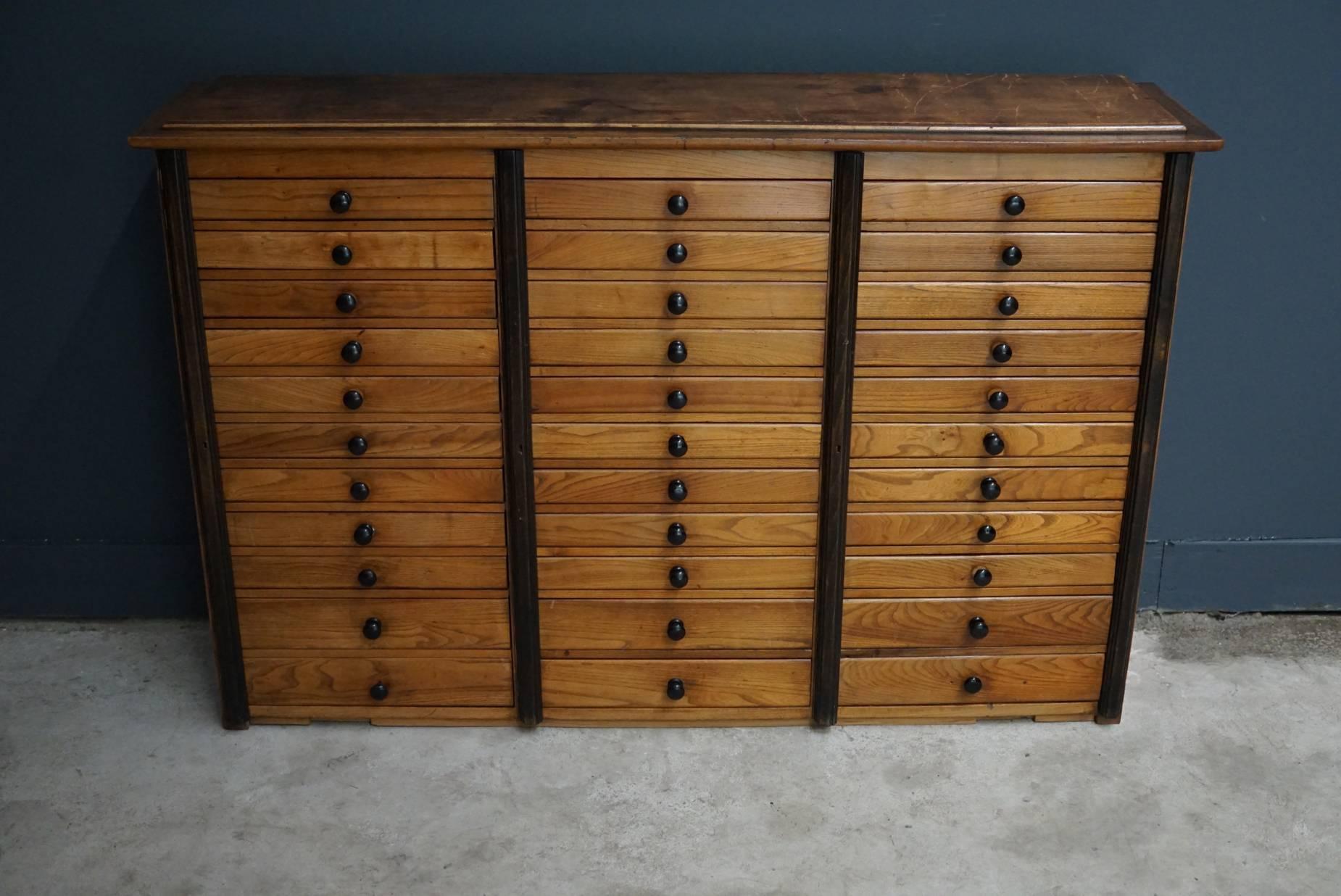 This apothecary cabinet was designed, circa 1950s in France. The cabinet is made from oak and features 33 drawers with black pulls. Most of the drawers have compartments and were used to store buttons.