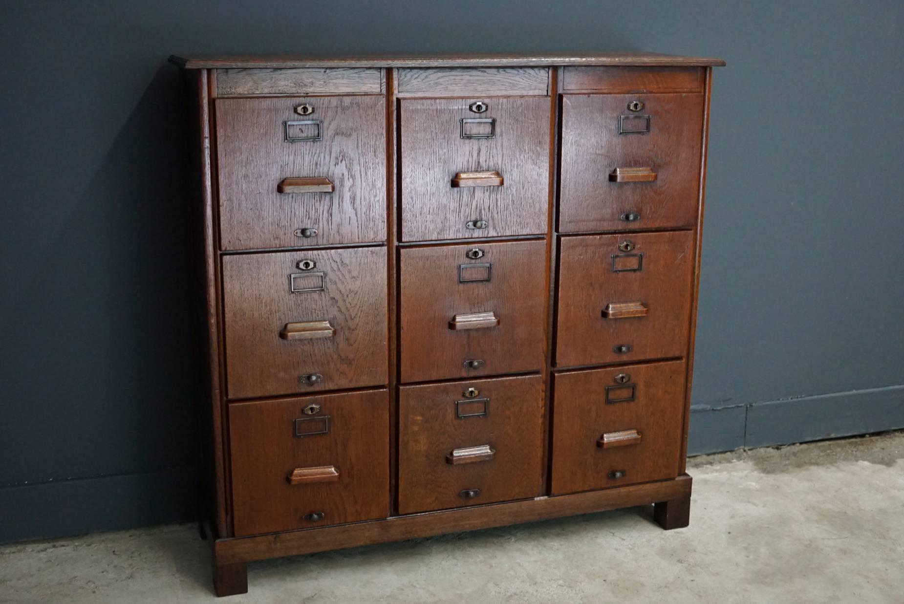 This filing cabinet was designed, circa 1930s in England. The cabinet is made from oak and features nine drawers with metal hardware and wooden handles.