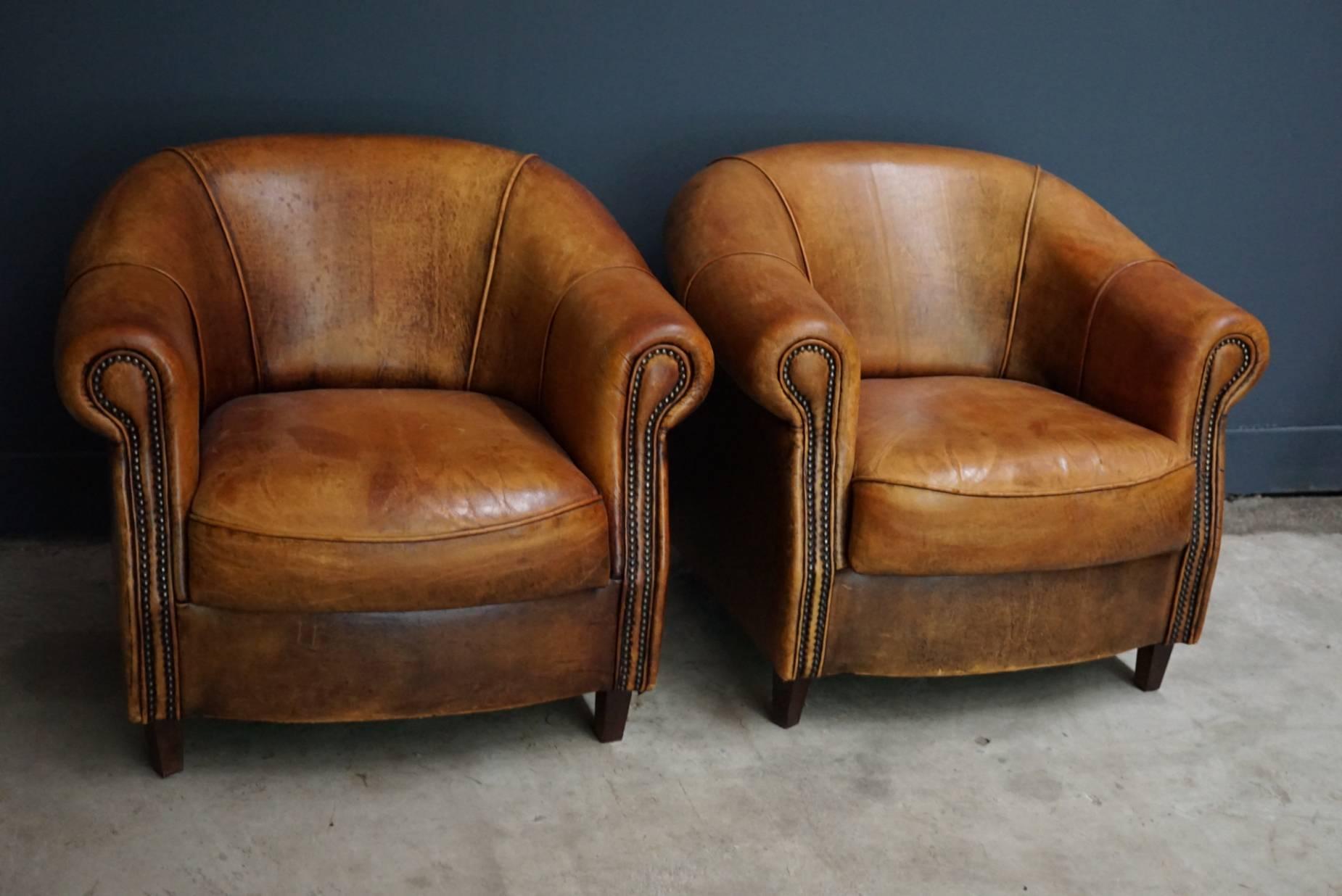 This pair of cognac-colored leather club chairs comes from the Netherlands. They feature rivets and wooden legs.