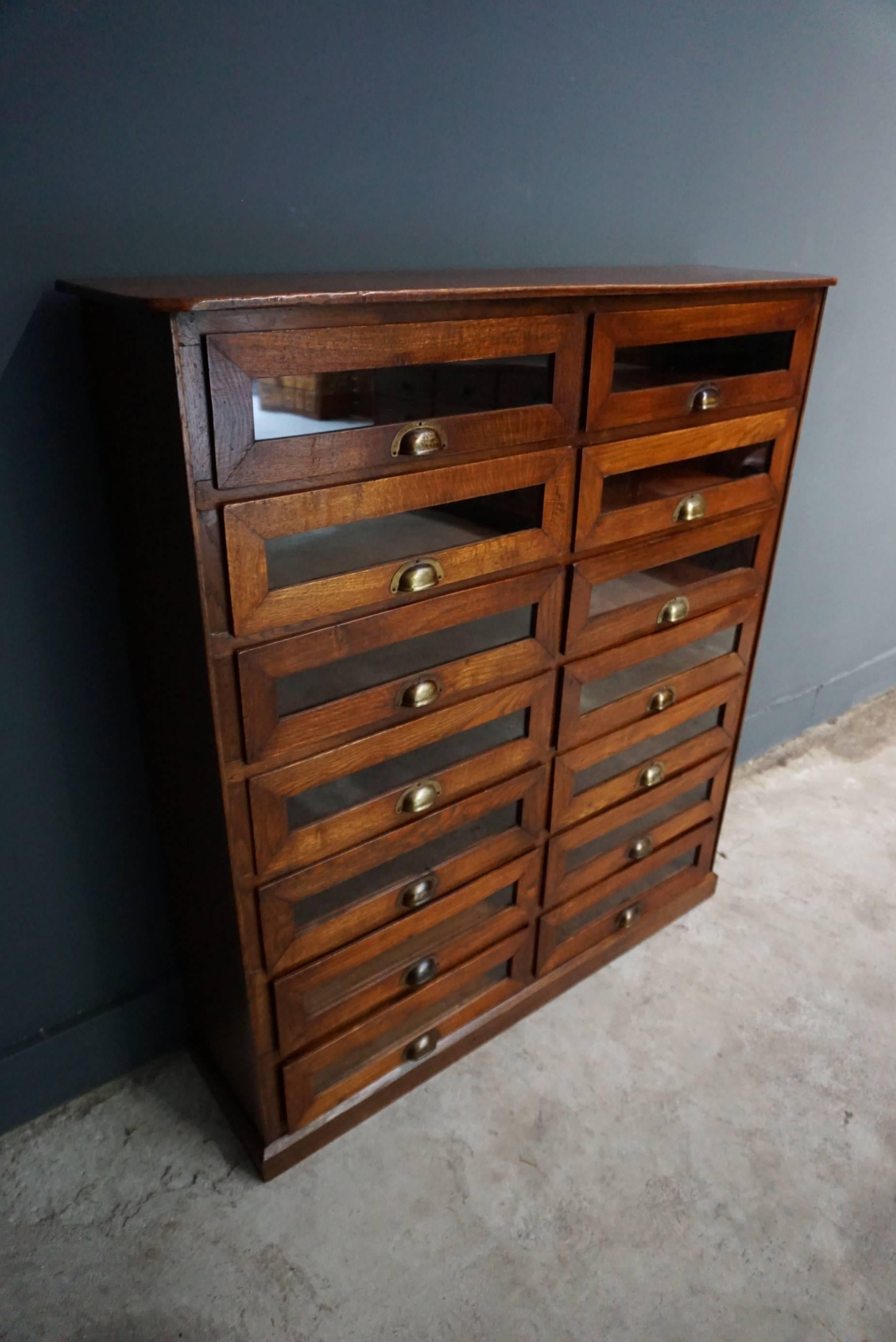 This vintage haberdashery shop cabinet originates from the United Kingdom. It is made from oak and features 14 drawers. It is restored and the drawers open and shut smoothly. The inside of the drawers measure 21.5 x 46 x 10.7 cm