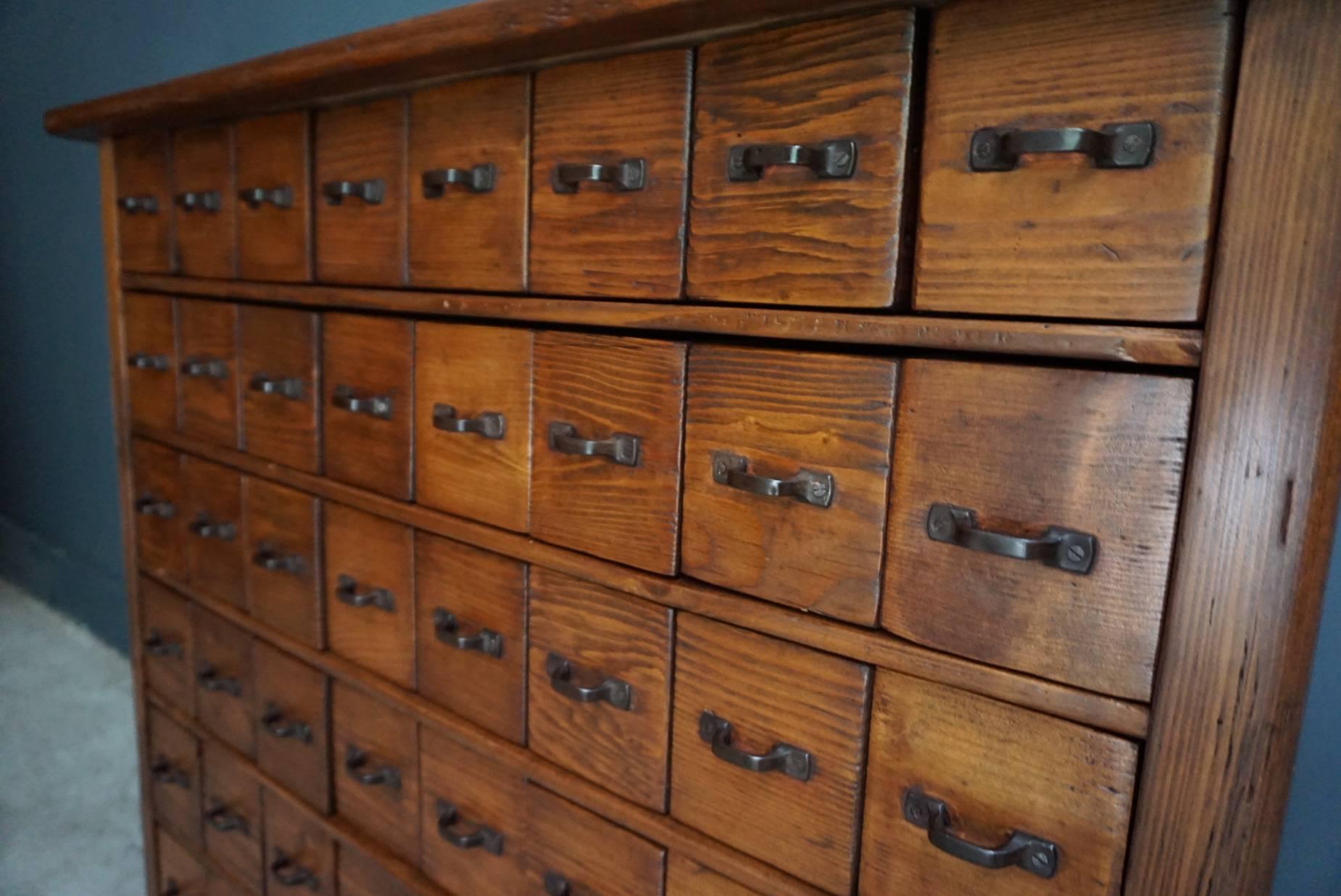 This vintage apothecary shop cabinet originates from France. It is made from pine and features 48 drawers. It is restored and the drawers open and shut smoothly. The large drawer at the bottom is not functional. The inside of the drawers measure