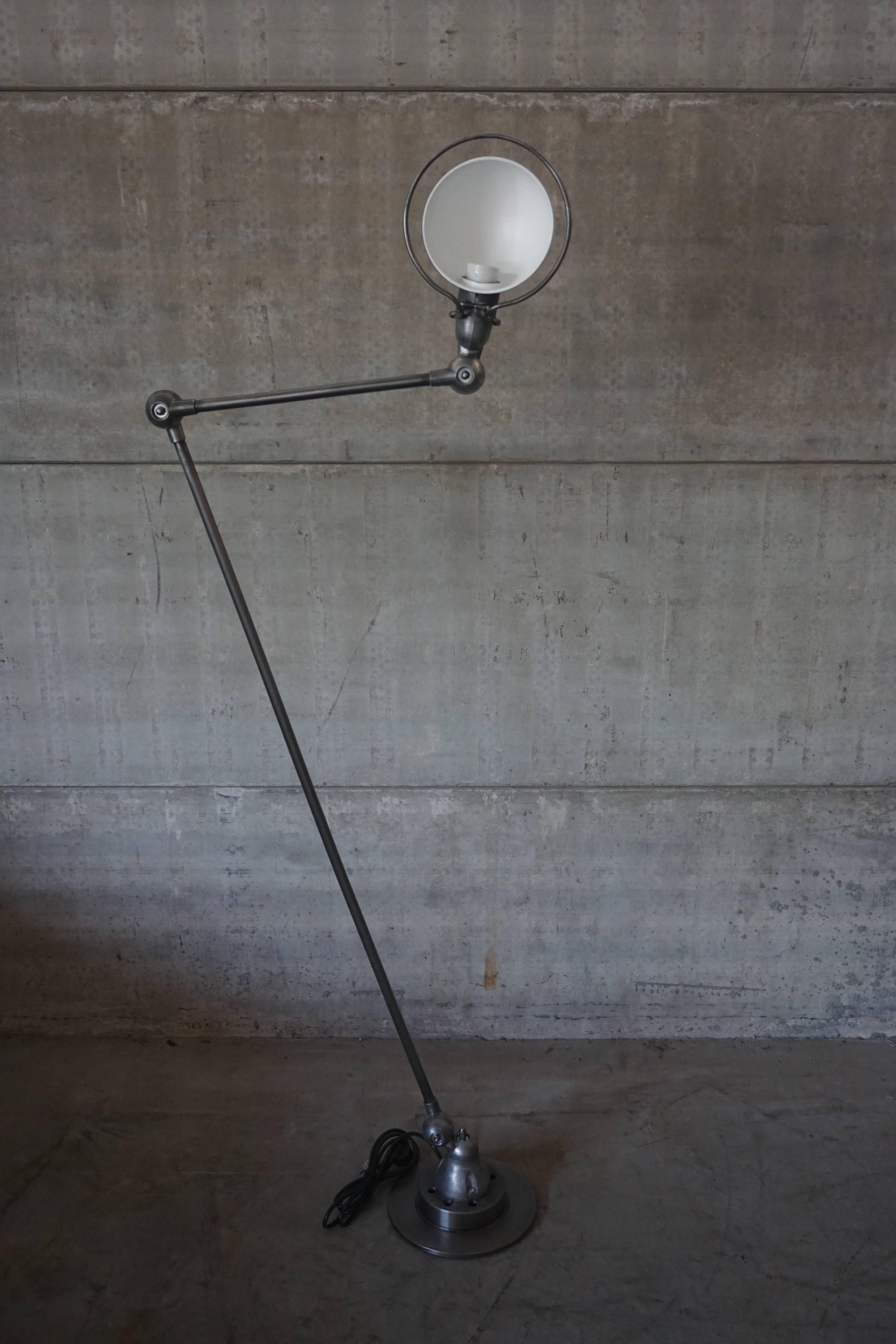 This two-armed floor lamp was manufactured in Lyon, France for Jieldé during the 1950s. The arms are made from brushed metal with graphite wax, which sits on a brake disk. In a good vintage condition and has been fully restored with new wiring with