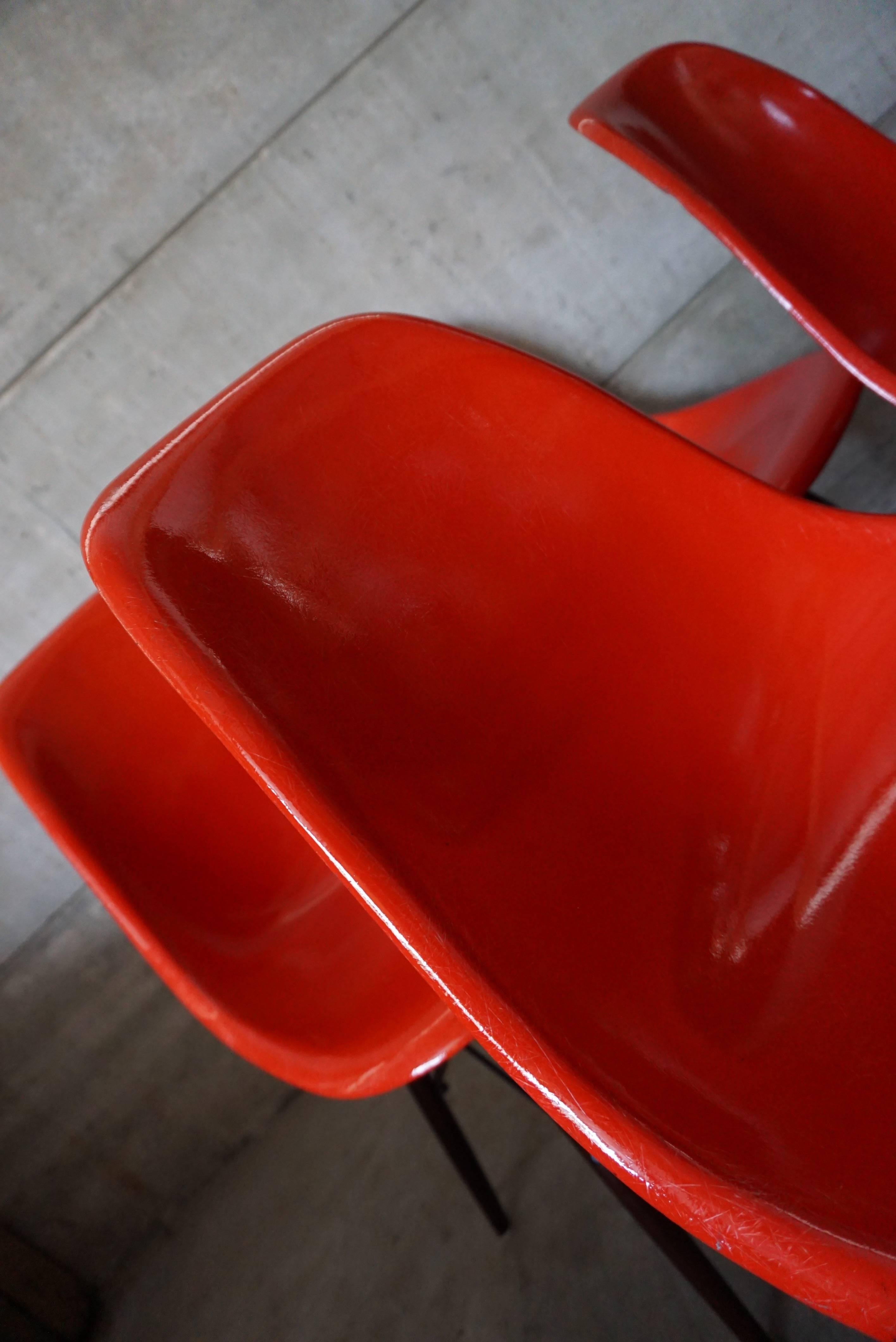 This vintage DSW dining chair set, consisting of four chairs, was designed by Charles & Ray Eames and manufactured by Herman Miller in the 1950s. This design classic features a red fiberglass seat which sits on wooden legs. It is in a good vintage