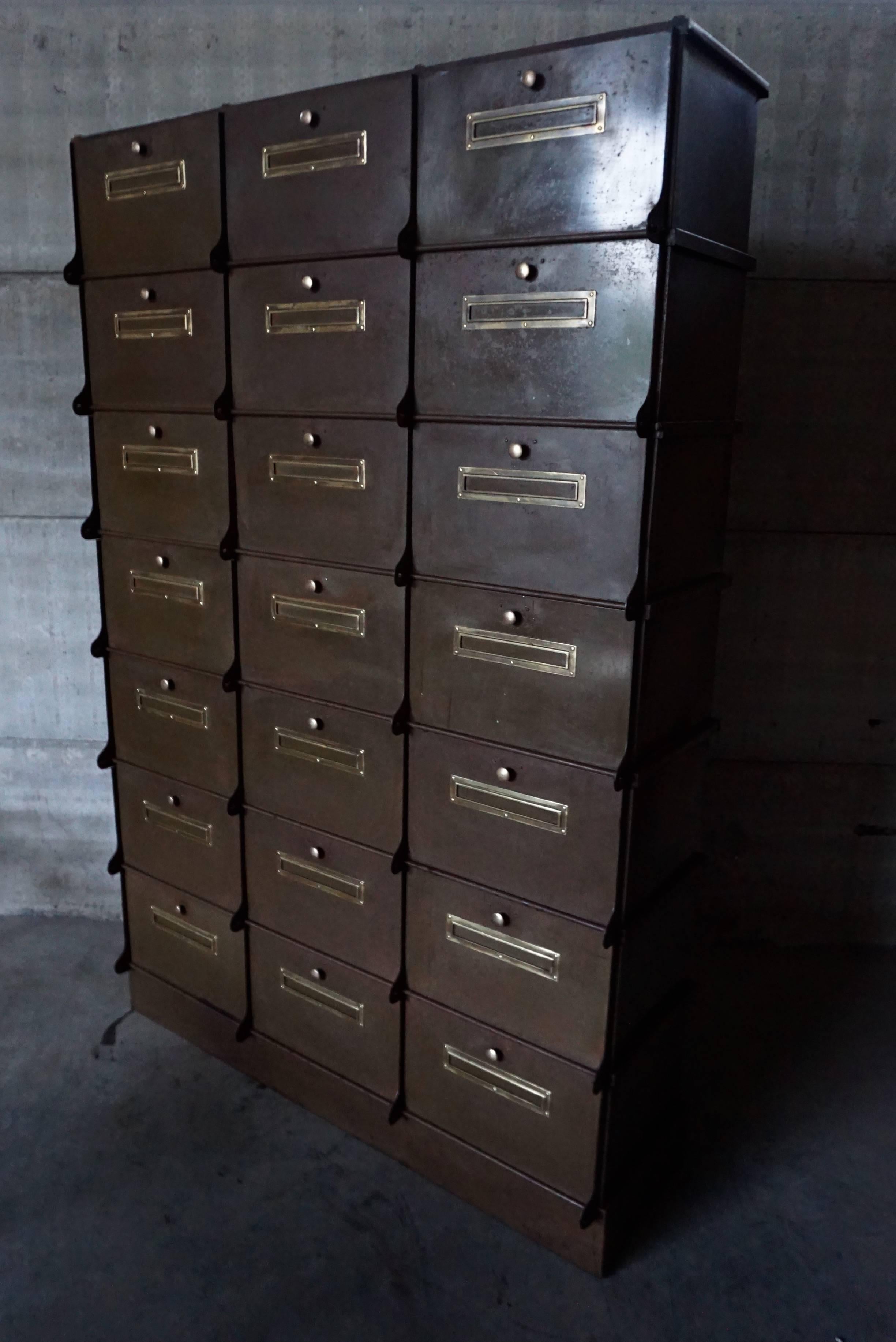 This industrial filing cabinet was manufactured in Belgium by Ribeauville during the 1930s. It is made from metal, featuring 21 compartments with brass details. The cabinet has been professionally restored and is in a very good vintage condition. 
