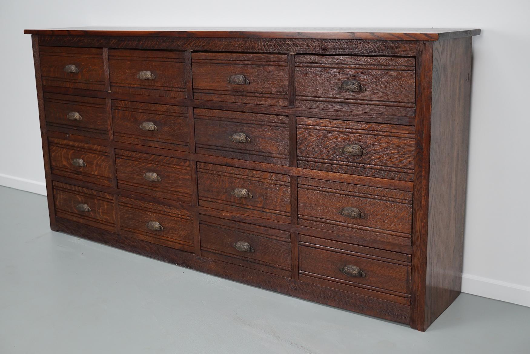 This hardware store cabinet was made around the 1920/1930s in France from oak. It features 16 large drawers with ornate cast iron handles. The interior dimensions of the drawers are: DWH 28 x 41 x 16 cm.