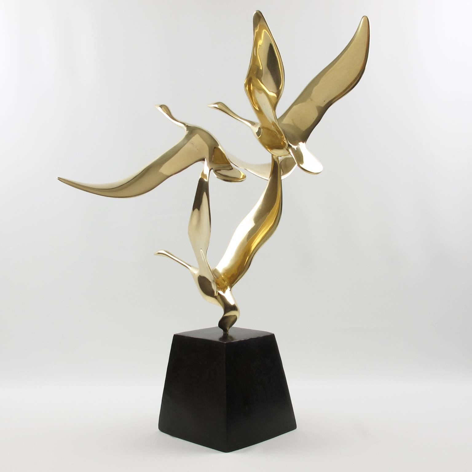 Elegant Mid-Century Modern polished brass sculpture featuring flying wild birds (very likely goose). Heavy geometric bronze base with original brown patina. The brass flying birds come off the bronze base (check picture). The modernist sculpture has