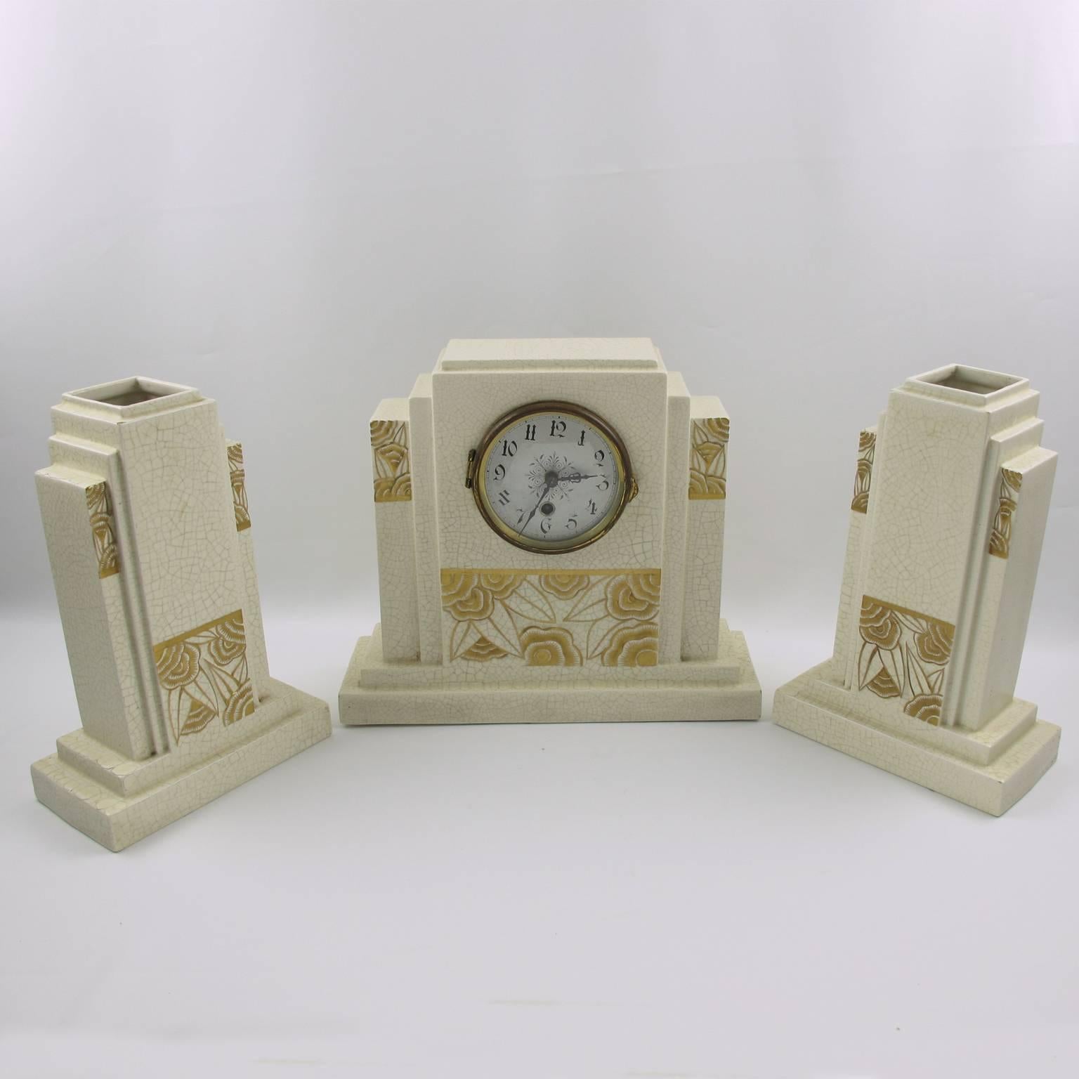 Elegant vintage Art Deco mantel clock set with garniture by Orchies Manufacturer, France. French ceramic body with white crackle glaze finish and carved typical Art Deco stylized floral design with gilt application. Impressive skyscraper geometric