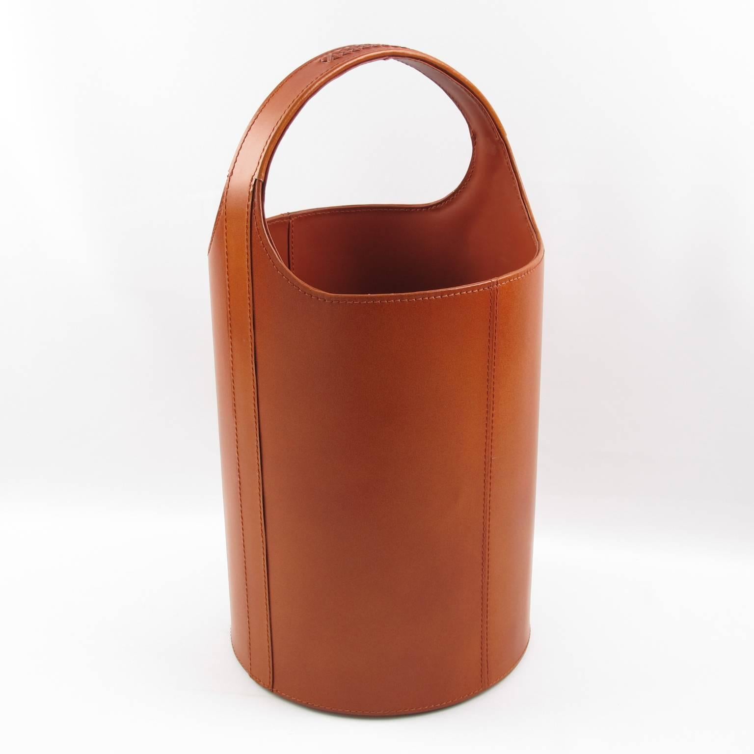 Elegant waste paper basket manufactured around 1960s in France. Large shape for extra body and stability. Made in cognac color leather imitation with assorted color stitching and braided design on handle. Excellent vintage