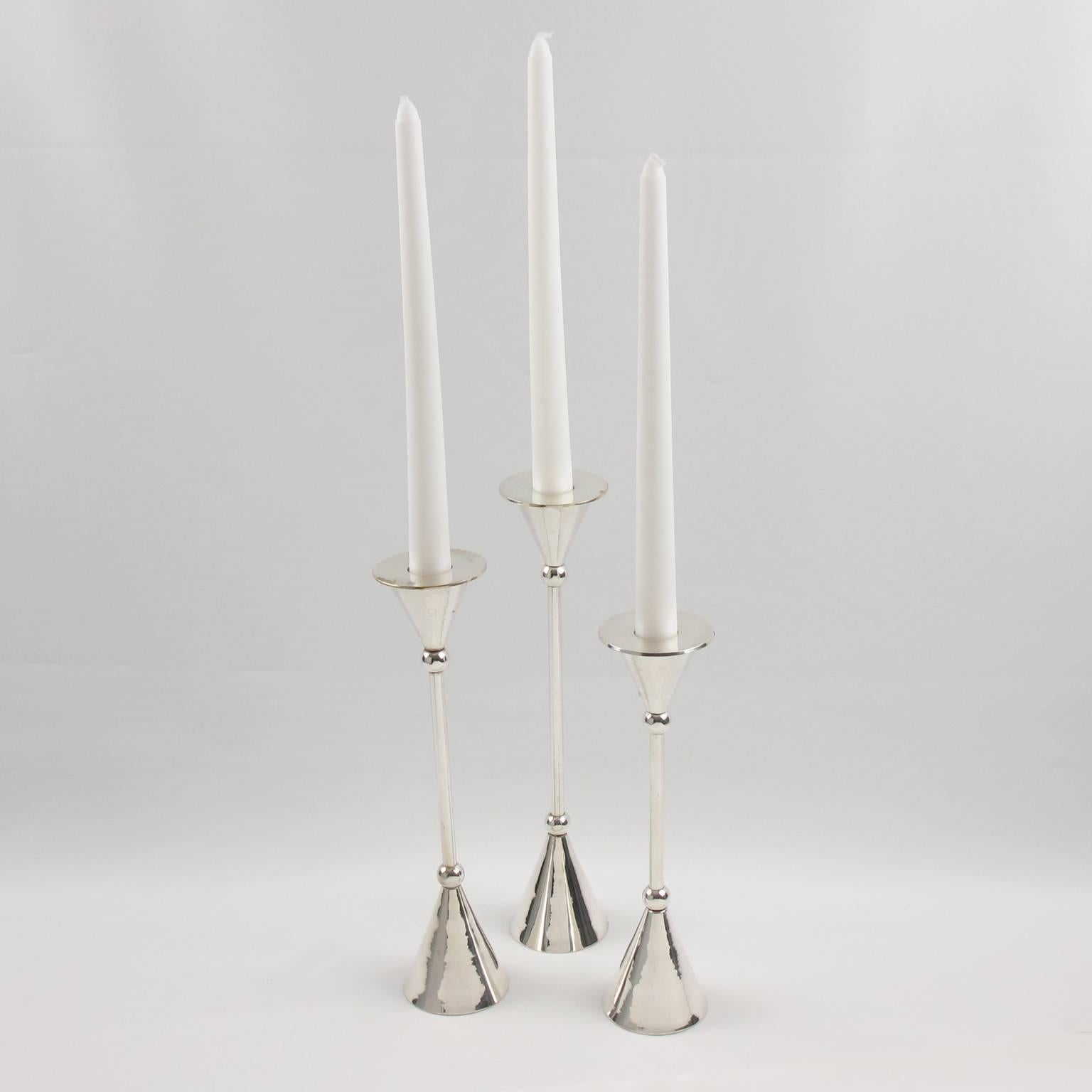 This Mid-Century Modern set of three silver plate candlesticks, candleholders has a wonderful simple sculptural design, reminiscent of Gio Ponti work. Graduated sizes with fluid lines. Perfect for any modern interior. No visible marking. (candles