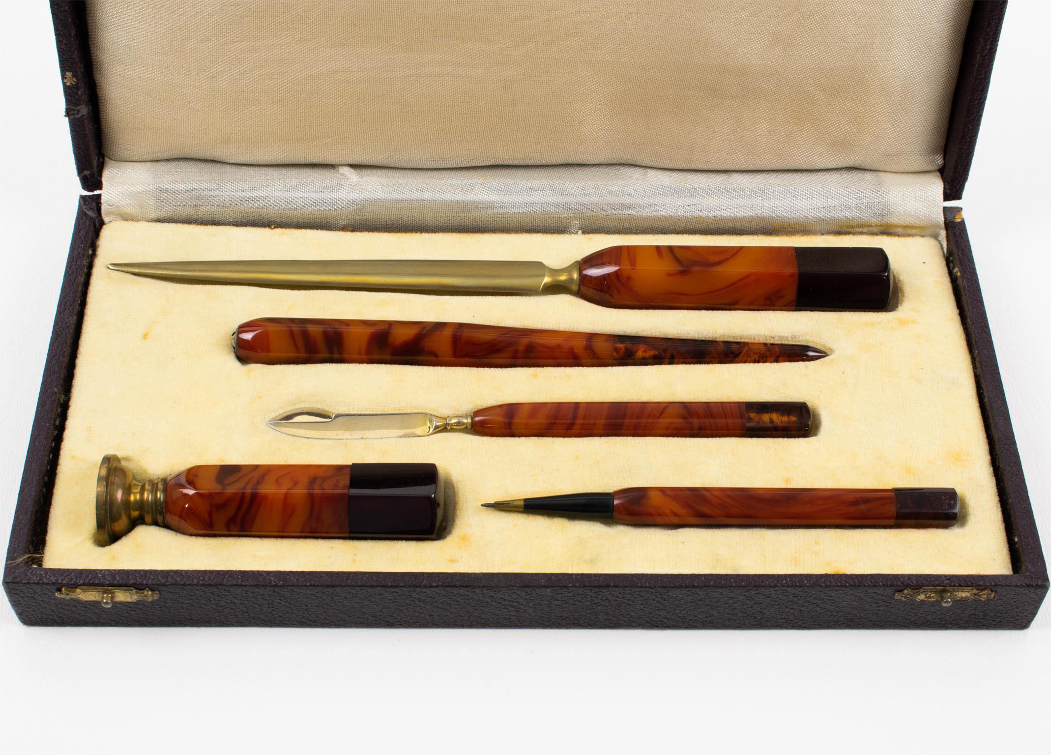 Dieses atemberaubende Art Deco Bakelit-Schreibset stammt aus den 1930er Jahren. Das Set besteht aus fünf Teilen in der Originalverpackung: einem Brieföffner, einem Papierschneider, einem Stifthalter, einem Druckbleistift und einem Wachsstempel.