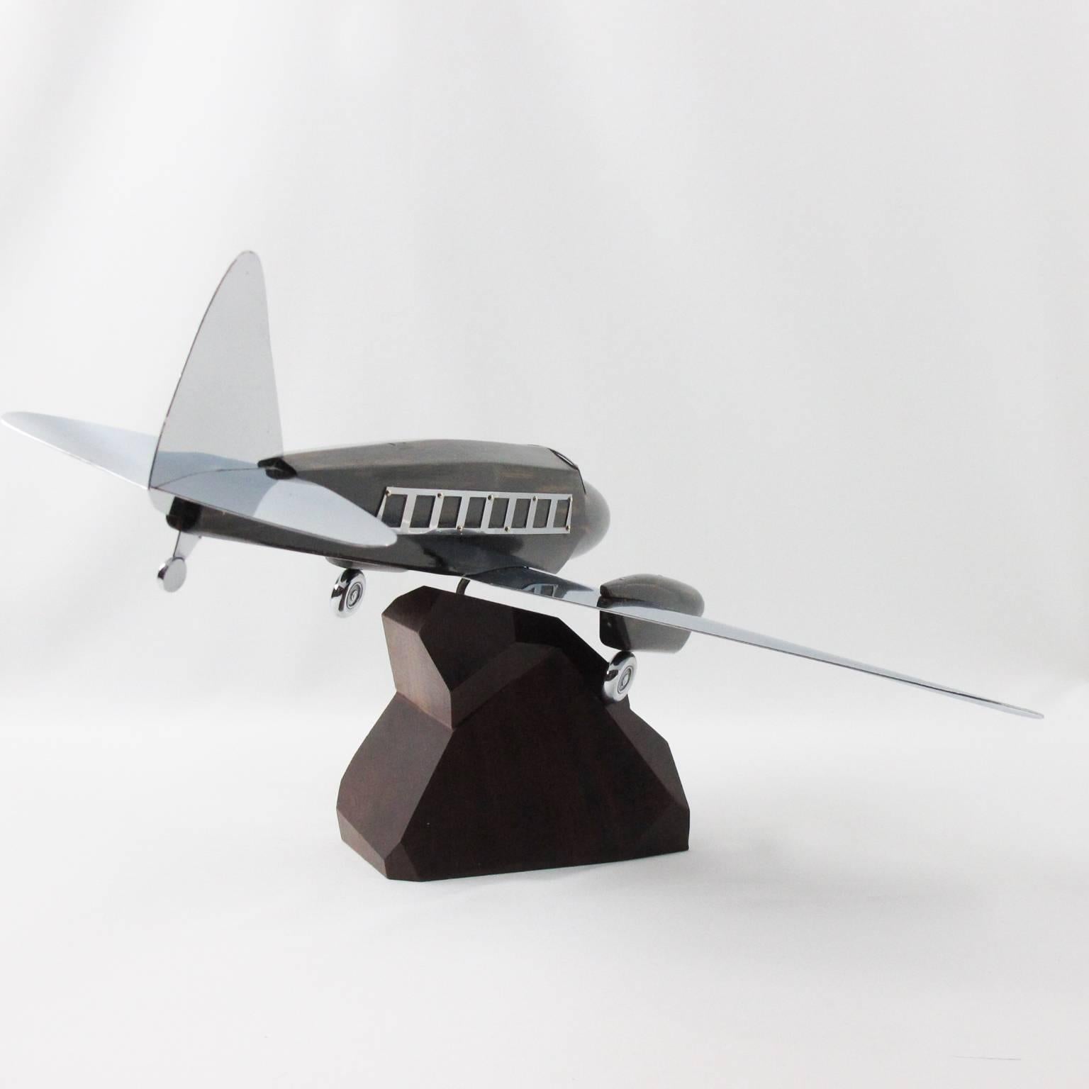 Stunning French Art Deco wood and chrome airplane model, mounted on a stylized wooden plinth. This large Art Deco Model airplane is made of solid wood with Macassar wood imitation textured pattern and chromed metal wings, tail, wheels and accents.