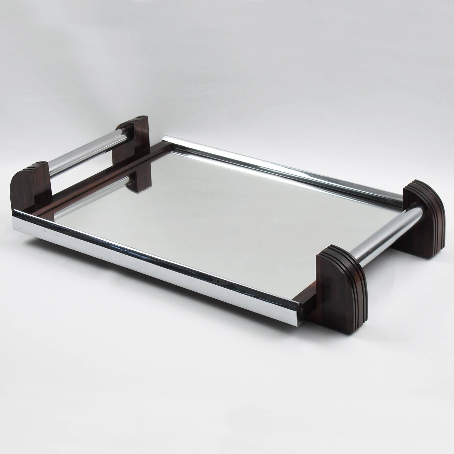 Elegant rectangular French Art Deco serving tray. Chromed metal gallery with tall solid Macassar wood carved handles. Insert base in mirror. Modernist design and geometric streamline shape offers all the elegance one could imagine for the finest