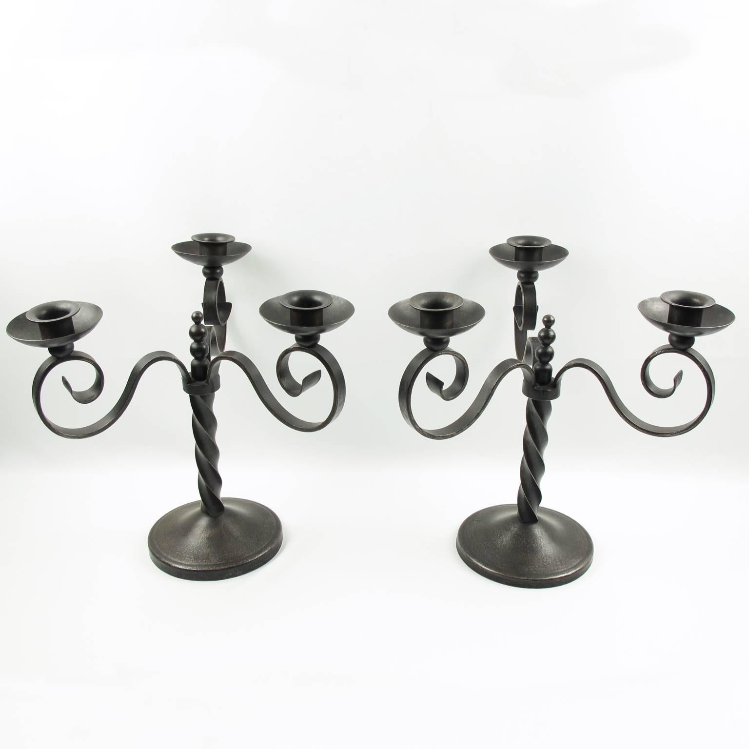 Pair of large wrought iron candelabras by Charles Piguet (1887-1942). Elegant three branches classic medieval inspired shape with original gunmetal patina. The candles-holders are both signed on base with monogram 