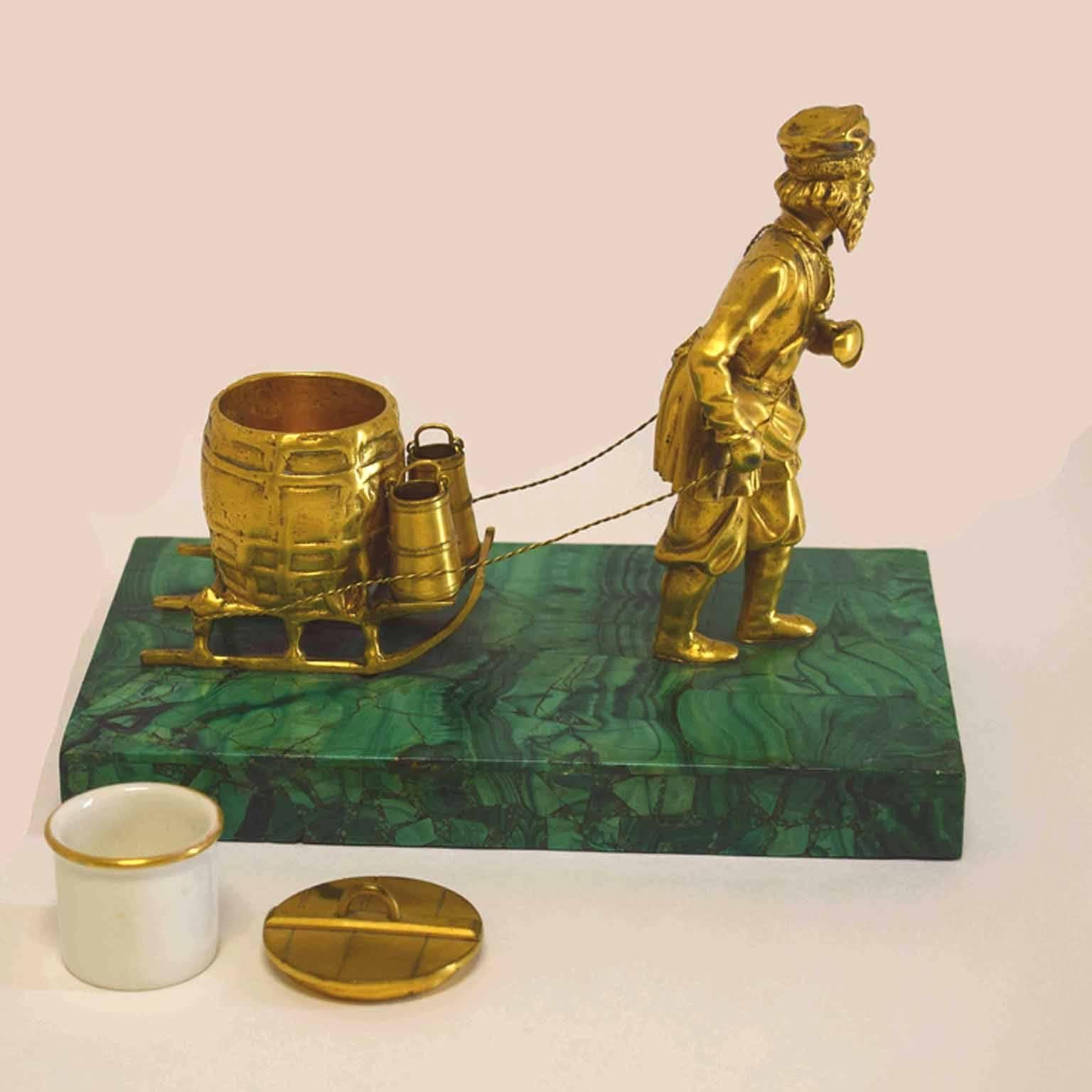 Inkwell of a peasant, sled and milk barrel with pails, {quill holders} the inkwell within the milk barrel, raised upon a malachite veneered plinth, {lacking rope}.