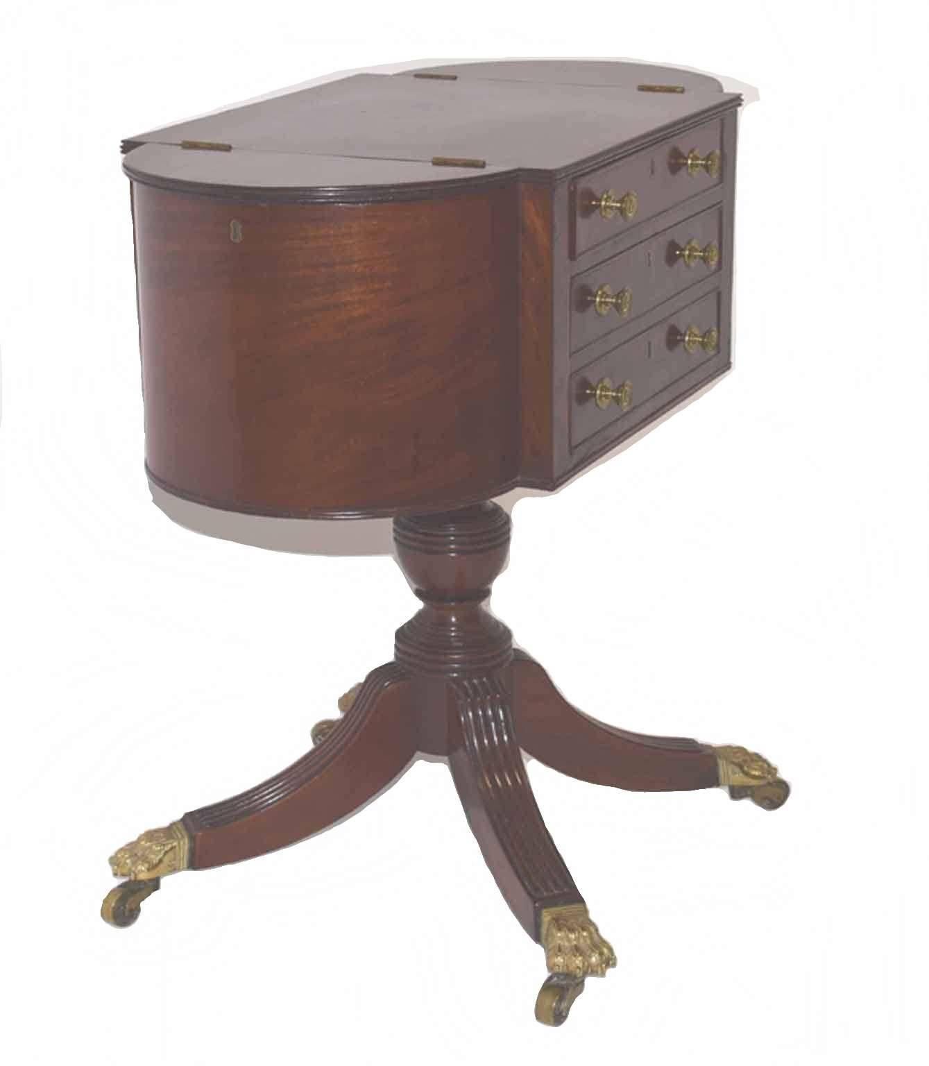 Mahogany work table in the style of Duncan Phyfe; the rectangular top with receded edge flanked by two half round compartments, fronted by three drawers, raised on baluster turned and receded pedestal, supported upon a quadripartite base with lion