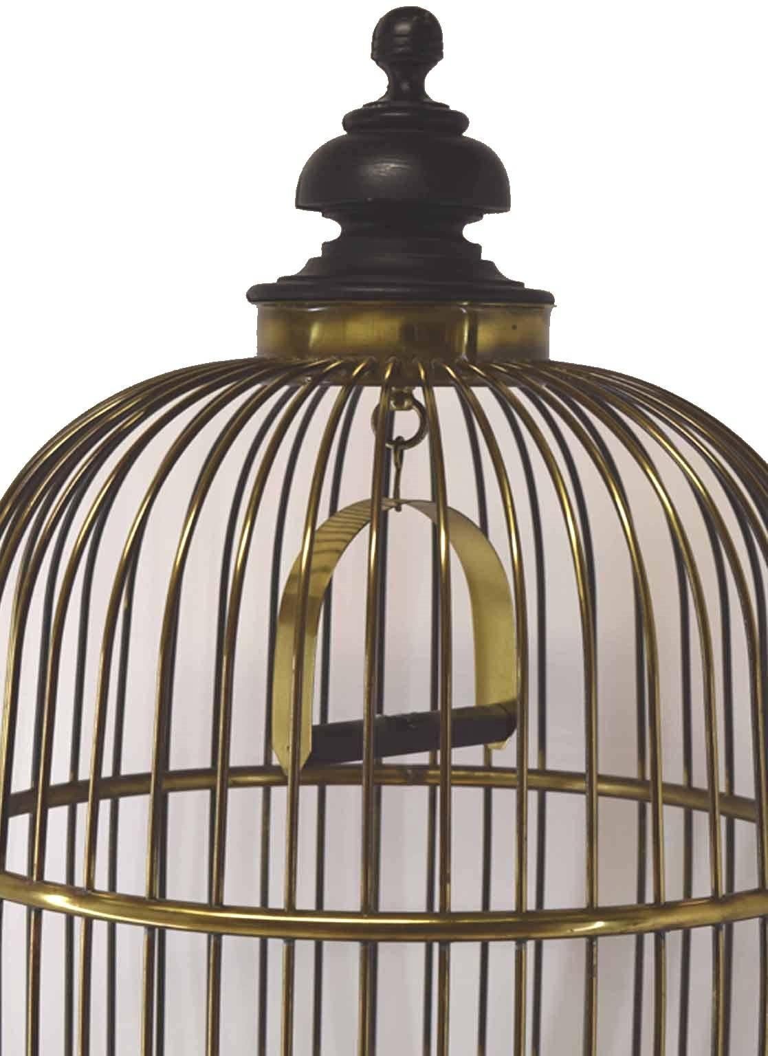 Antique brass and wire ebonized wood parrot cages and faux bamboo stands; of far eastern inspiration, the bell shaped cages with large  ebonized turned finals, removable trays, complete with feeders and slide wire doors, custom bamboo stands of