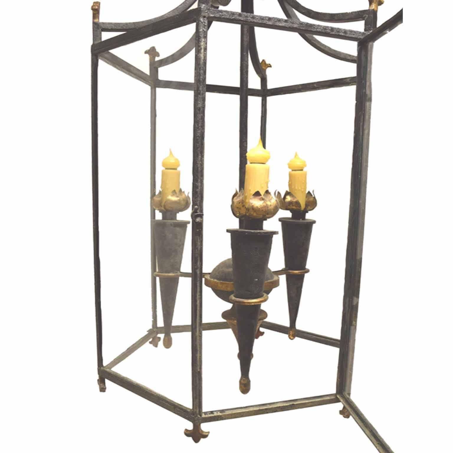 French antique Napoleon brass and gilt hexagonal lantern; with a gathered leaf corona suspending a glass cage with fleurs-de-lisat the joints, centered by three brass and tole peinte torchers, joined to a sphere and finial, circa 1860.