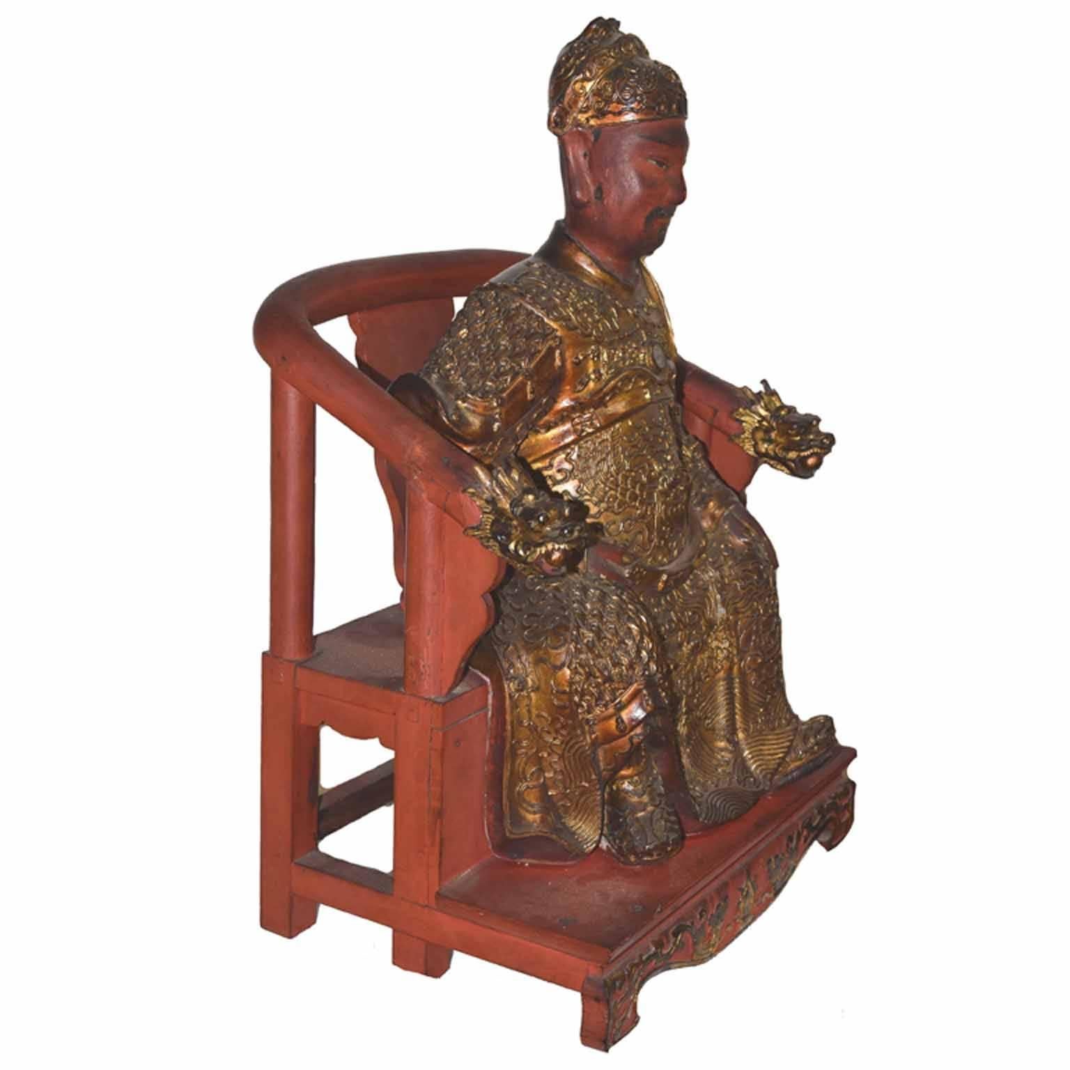 Antique Chinese gold leaf hand-carved period figure of a mandarin aristocrat seated on a dragon armed throne chair, wearing an elaborate silk embroidered robe, belted at the waist, with cloud scrolls, dragons and hanging tassels, a silvered mirror