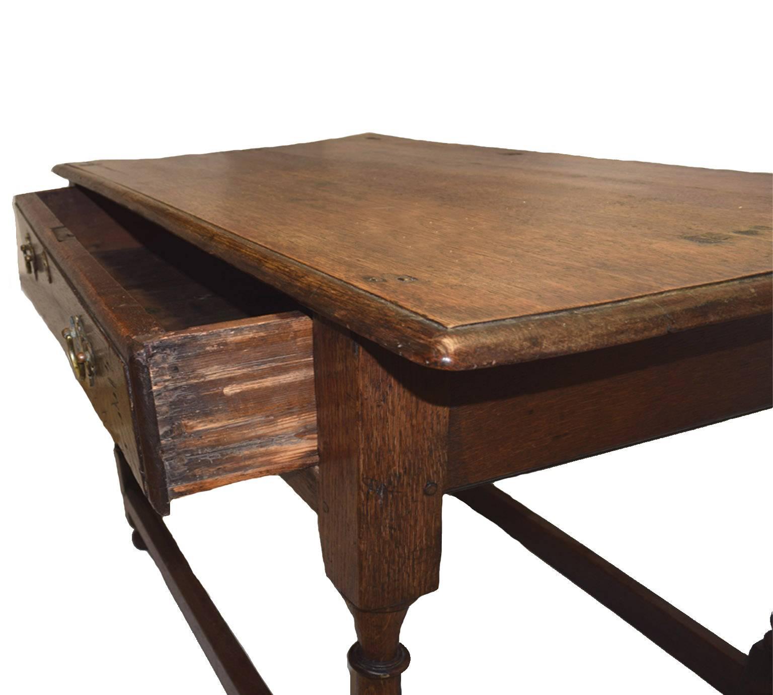 Antique William and Mary side table; with a plank top having an ogee rim, the apron having a single drawer, raised on four vasi-form turned and blocked legs united by four moulded cross stretchers, supported upon four bun feet, circa 1690.