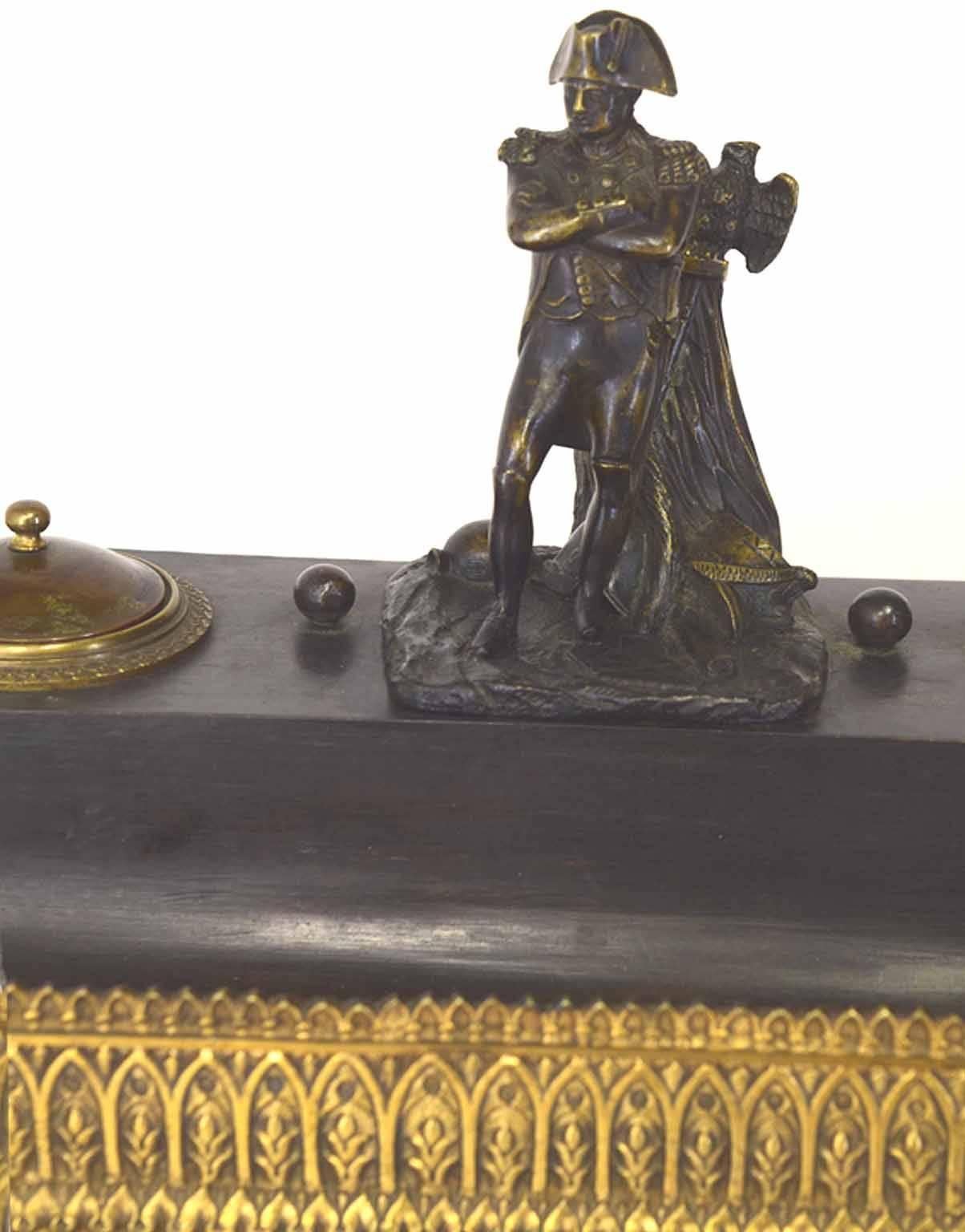 Antique French Charles X period ormolu and painted bronze necessaire de bureau; the raised gallery centered by a standing figure of Napoleon I beside his eagle standing, helmets and cannon ball, flanked by a circular domed ink well and sander, above