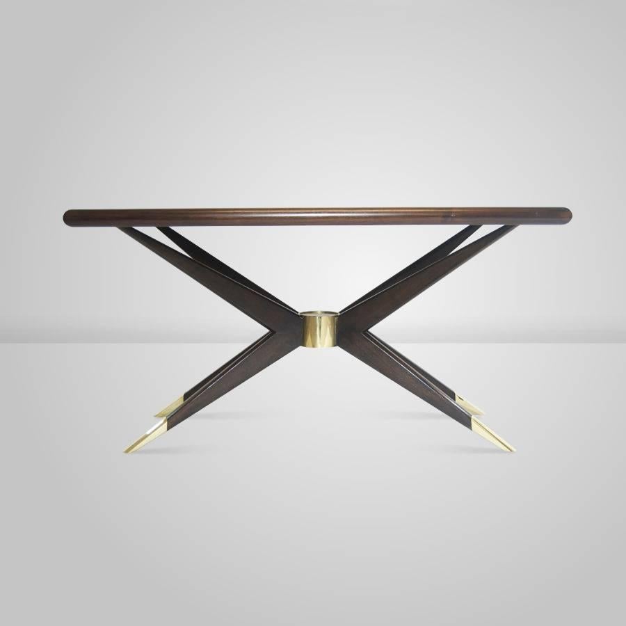 Gio Ponti inspired coffee table. Shown in solid walnut in a dark finish; turned, tapered, splayed arms and legs converge on a brass nucleus, complimented beautifully by sabots of the same finish.

Available in custom sizes and finishes.

     