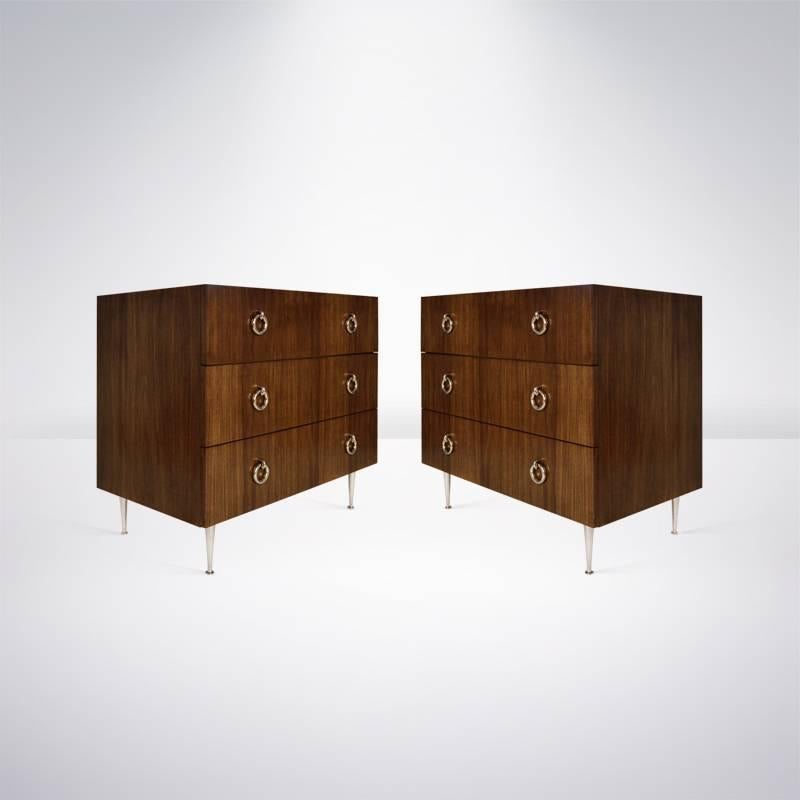 Walnut cases done in a medium finish on hand casted and polished, solid nickel legs. Each chest features three large drawers, providing ample storage, highlighted by door-knocker style hardware. 