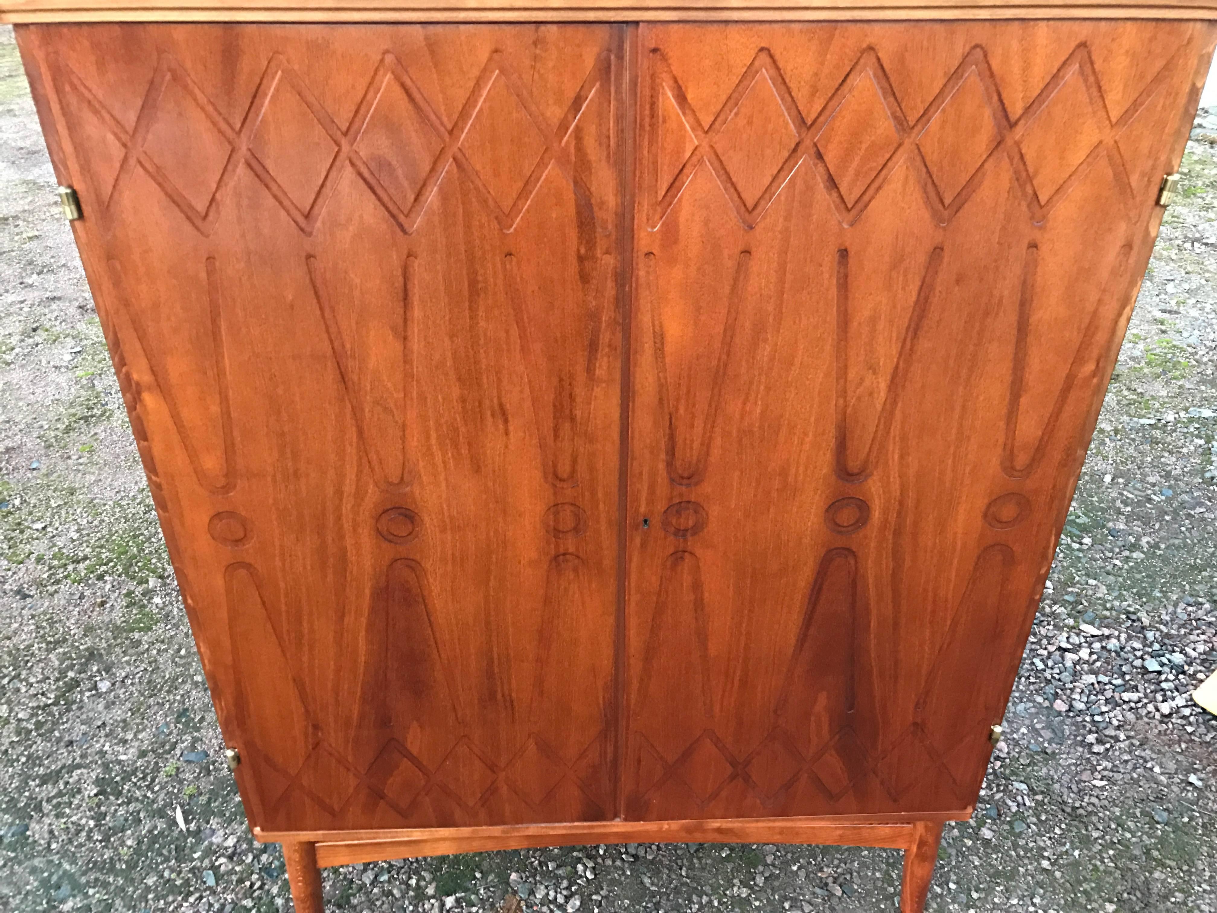 Nice Midcentury cabinet in teak/mahogany by Yngve Ekström for Westbergs Möbler (Sweden). Two beautiful doors with milled relief decor, interior with pullout trays and shelves. Legs in beech, unusual model.

Yngve Ekström had his personal style,