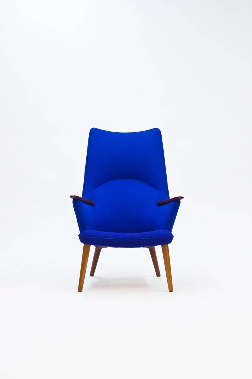 Impressive and inviting AP-27 lounge chair by Hans J. Wegner designed in 1954. Upholstered with wool Kvadrat fabric in two shades of blue, the seat having a slightly more purple nuance. The teak details on the armrests adds to the refinement of the