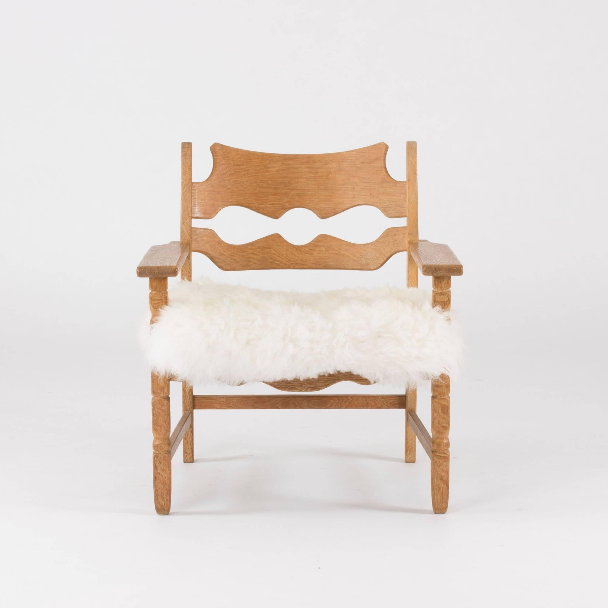 Very cool “Razor Back” lounge chair by Henning Kjaernulf, in a rustic meets modernism design. Made of oak with beautiful wood grain, upholstered with sheepskin.