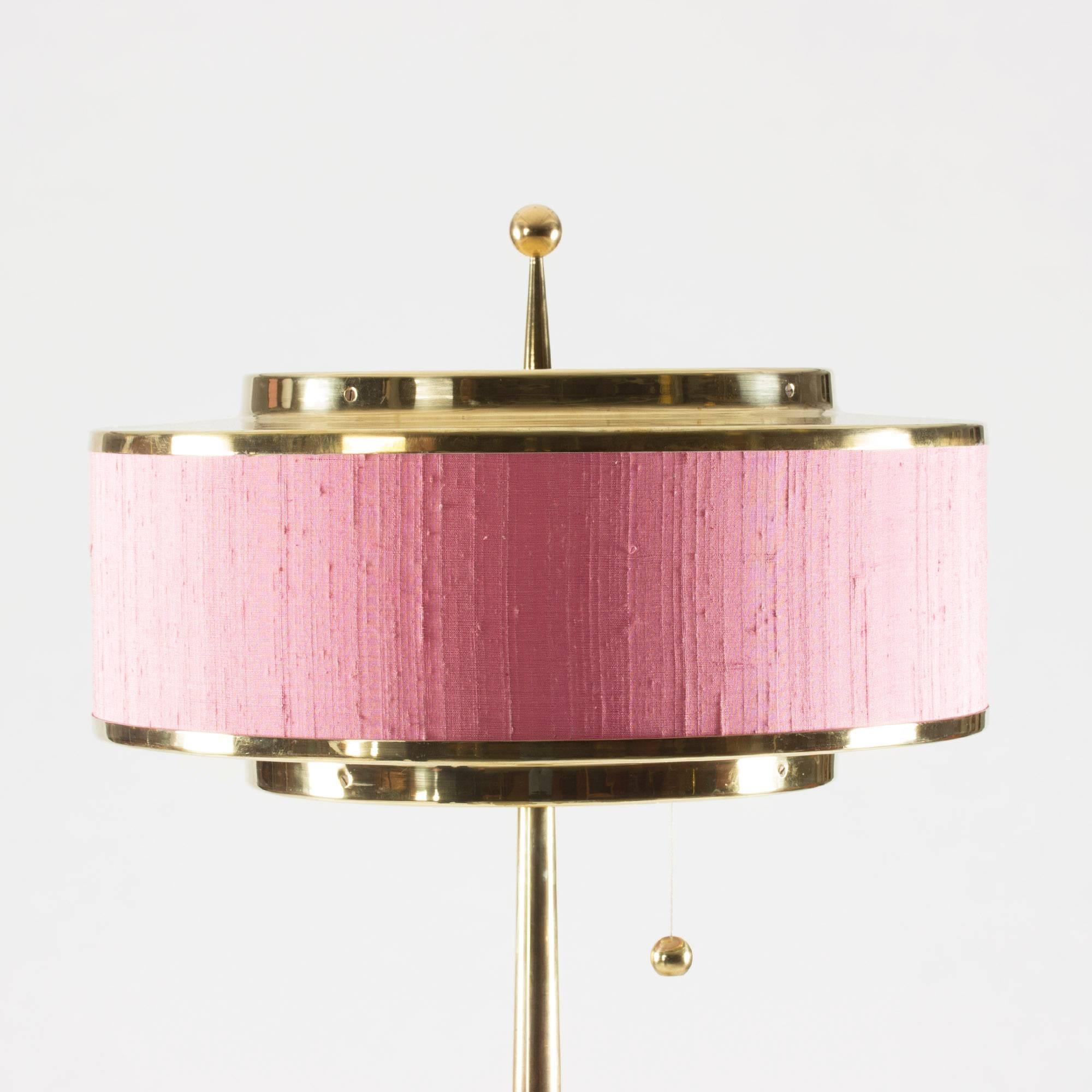 Oversized brass table lamp by Hans-Agne Jakobsson. Unusually tall and perfect proportions, and a lampshade that grants this statement piece both Space Age and oriental vibes. Reupholstered with pink raw silk.