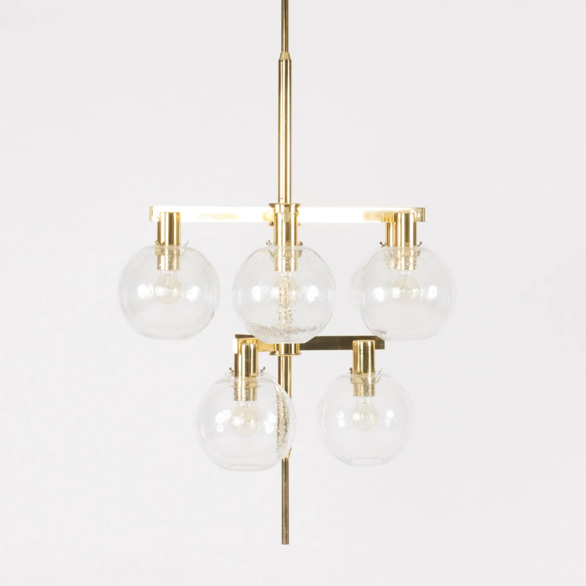 Striking brass chandelier by Hans-Agne Jakobsson with nine glass shades set at two heights. The shades have enclosed air bubbles that make them very decorative both lit and unlit.

We will adjust the height of the pole to the desired measurements.